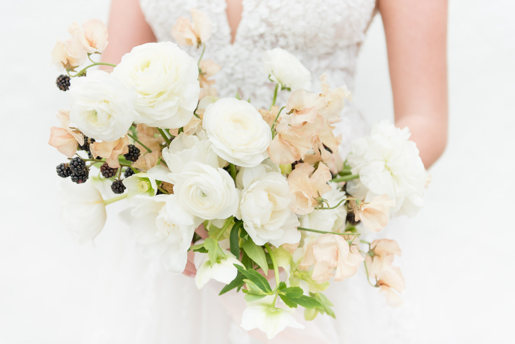Bride holds white and blush flowers.