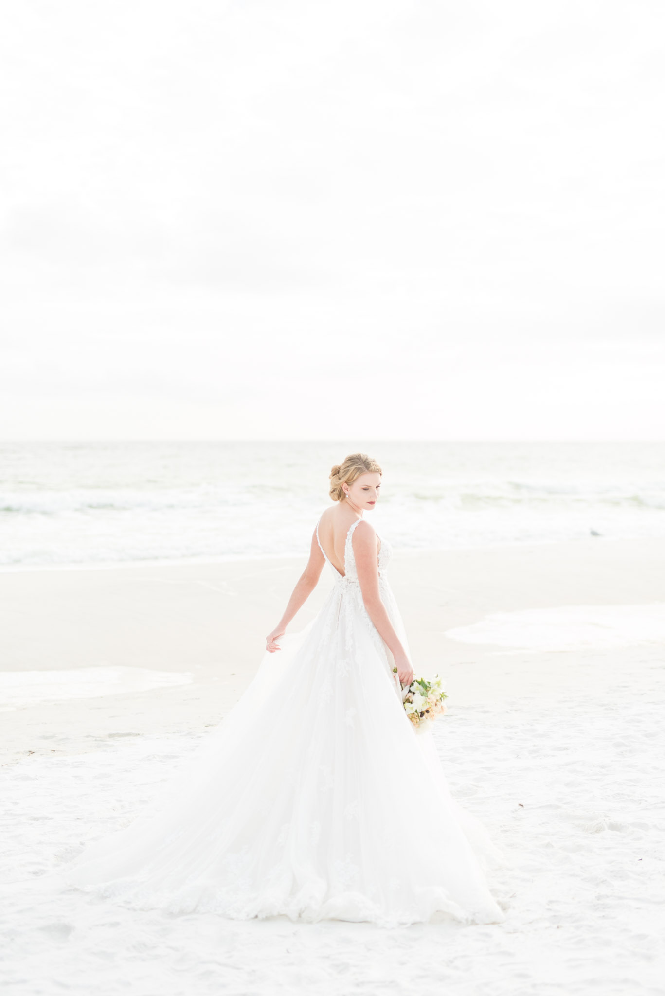 Bride looks over shoulder on sunset beach.