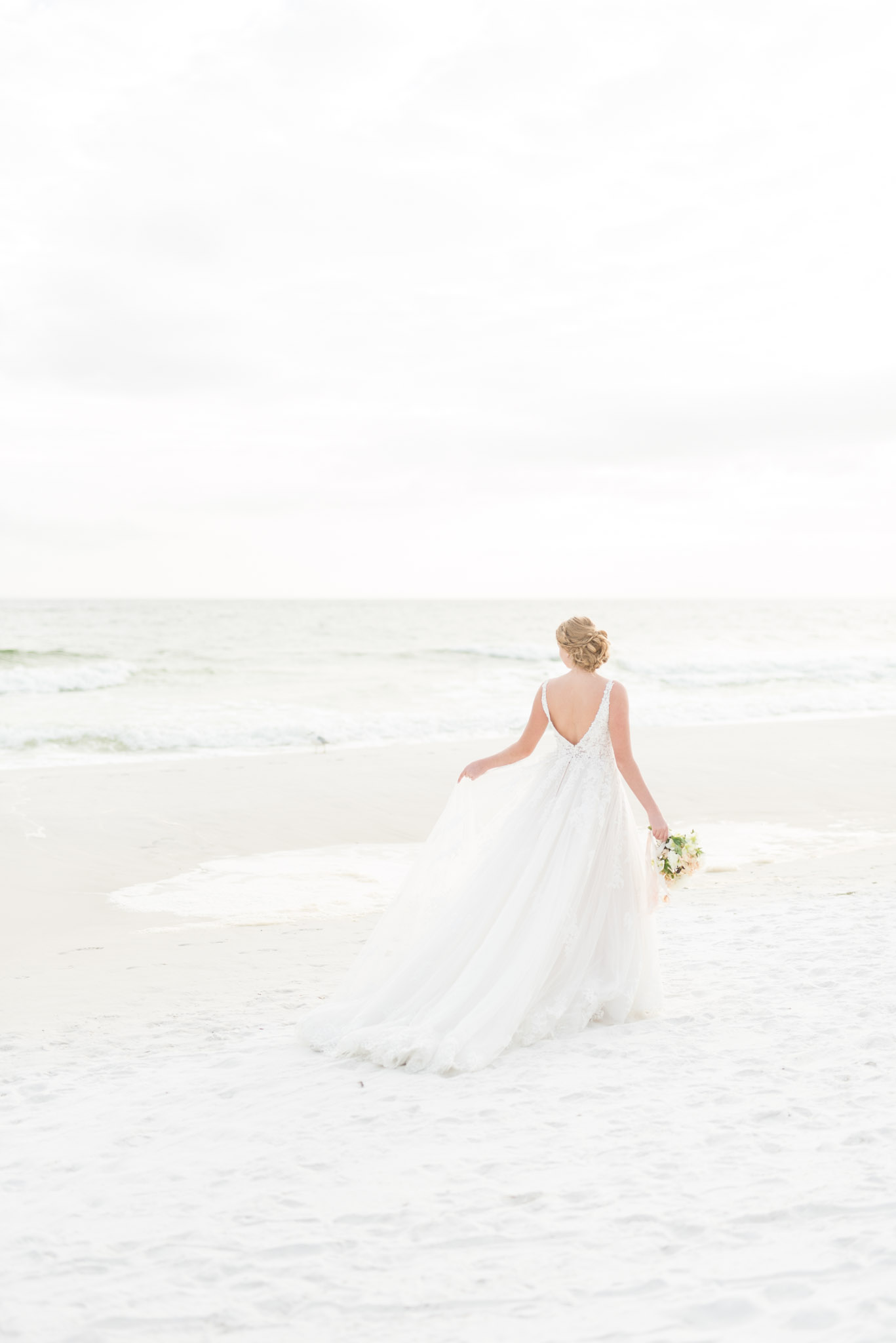Bride walks on sunset beach.