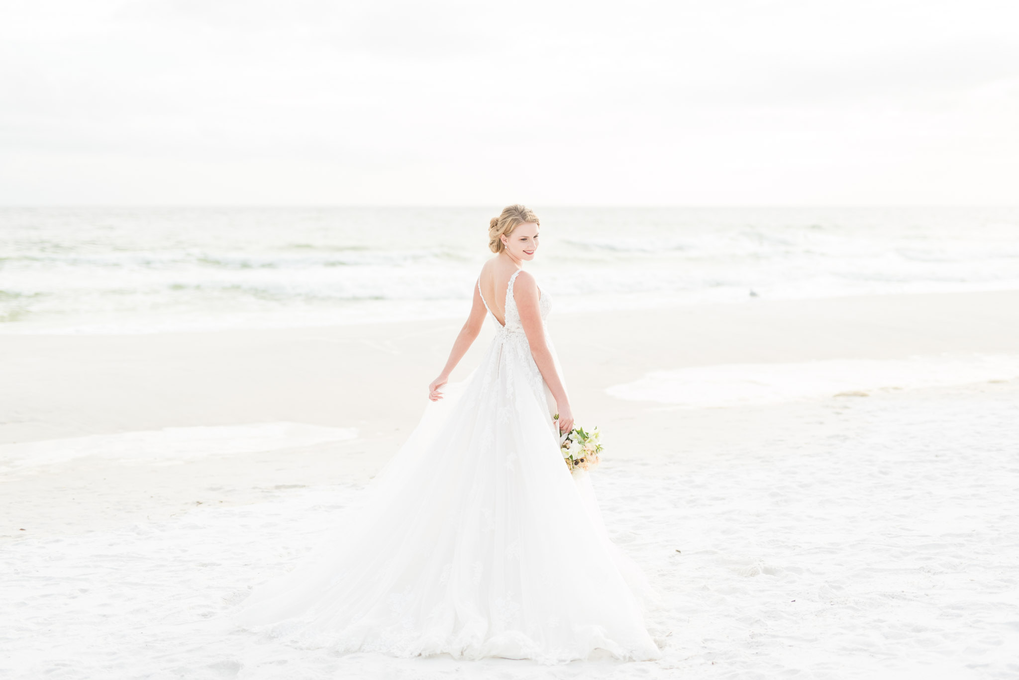 Bride looks over shoulder on Destin beach.