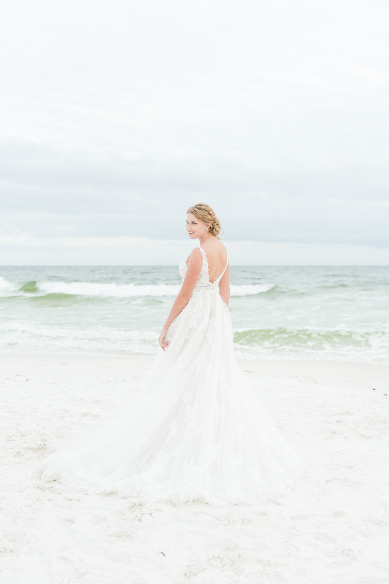 Bride stands next to ocean.