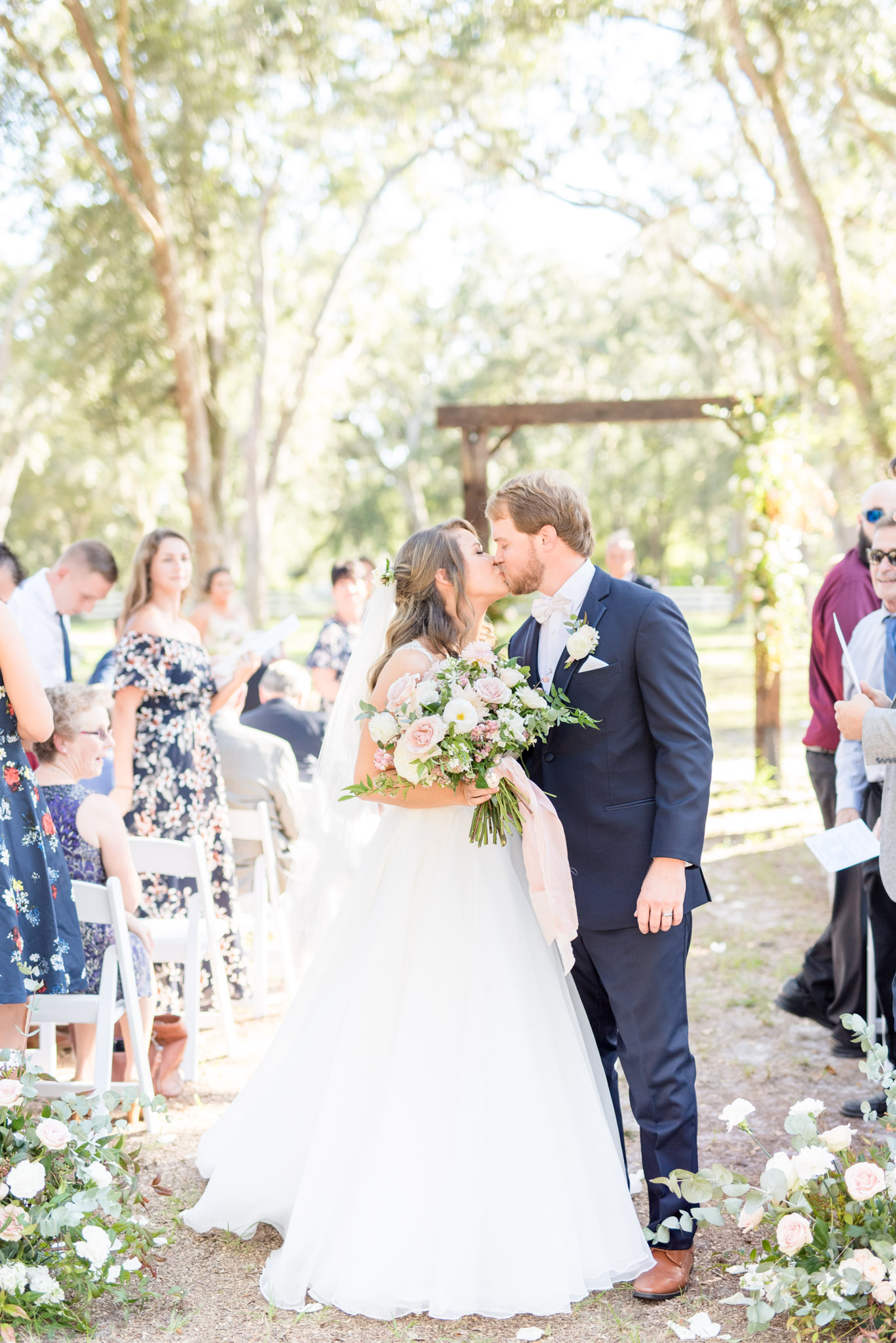 Bride and groom kiss at the end of the aisle.