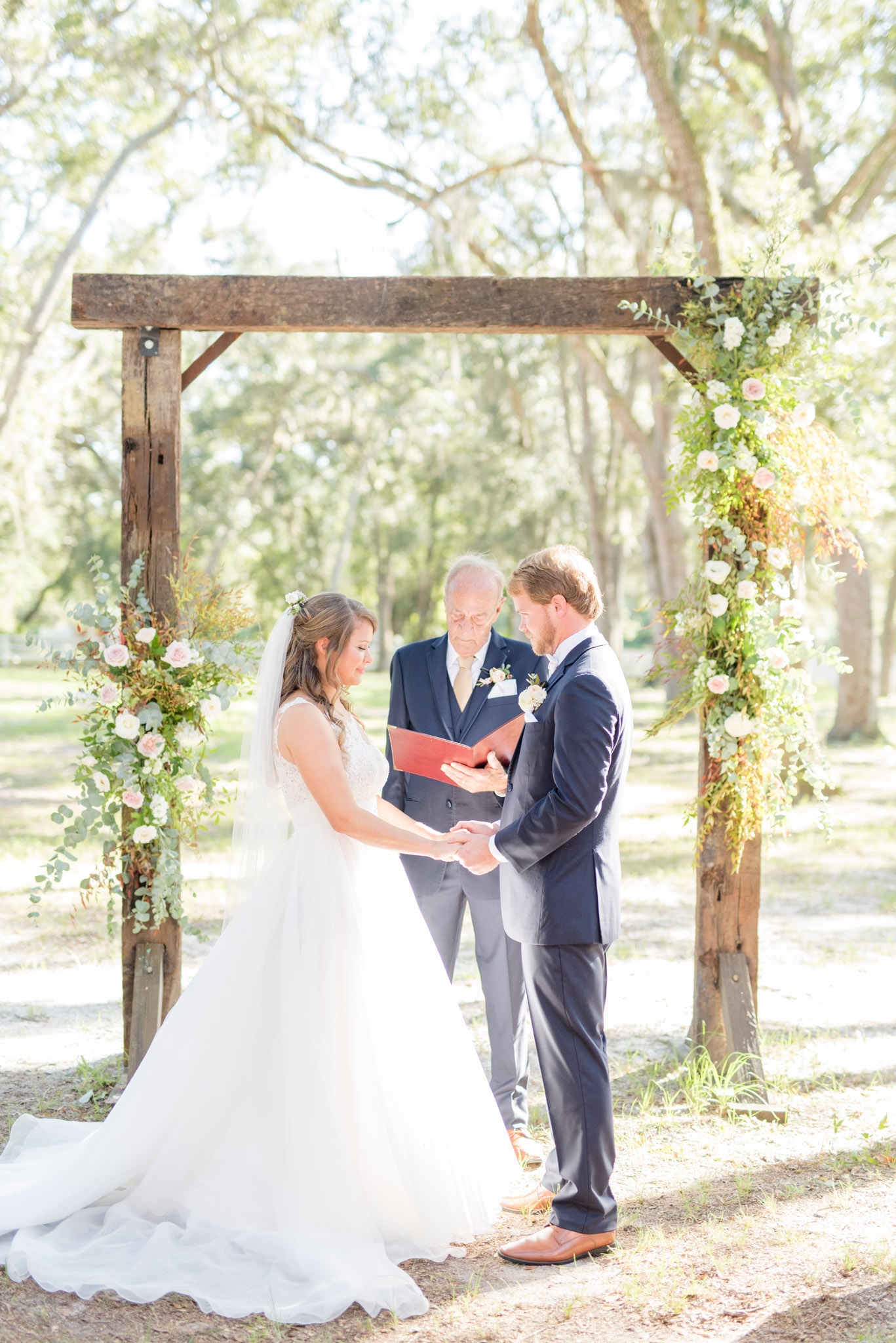 Bride and groom hold hands during wedding ceremony.