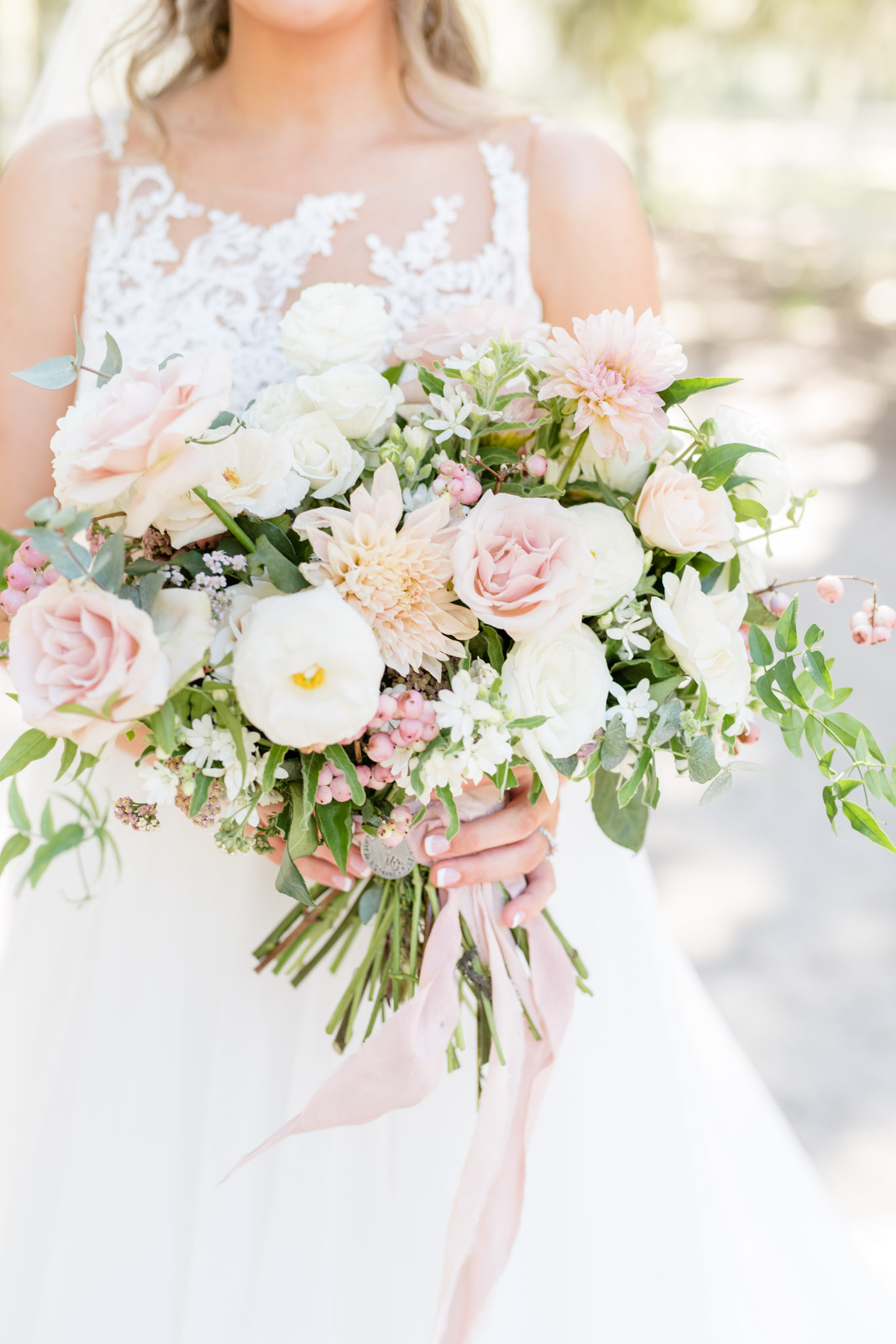 Bride holds pink and white wedding flowers.