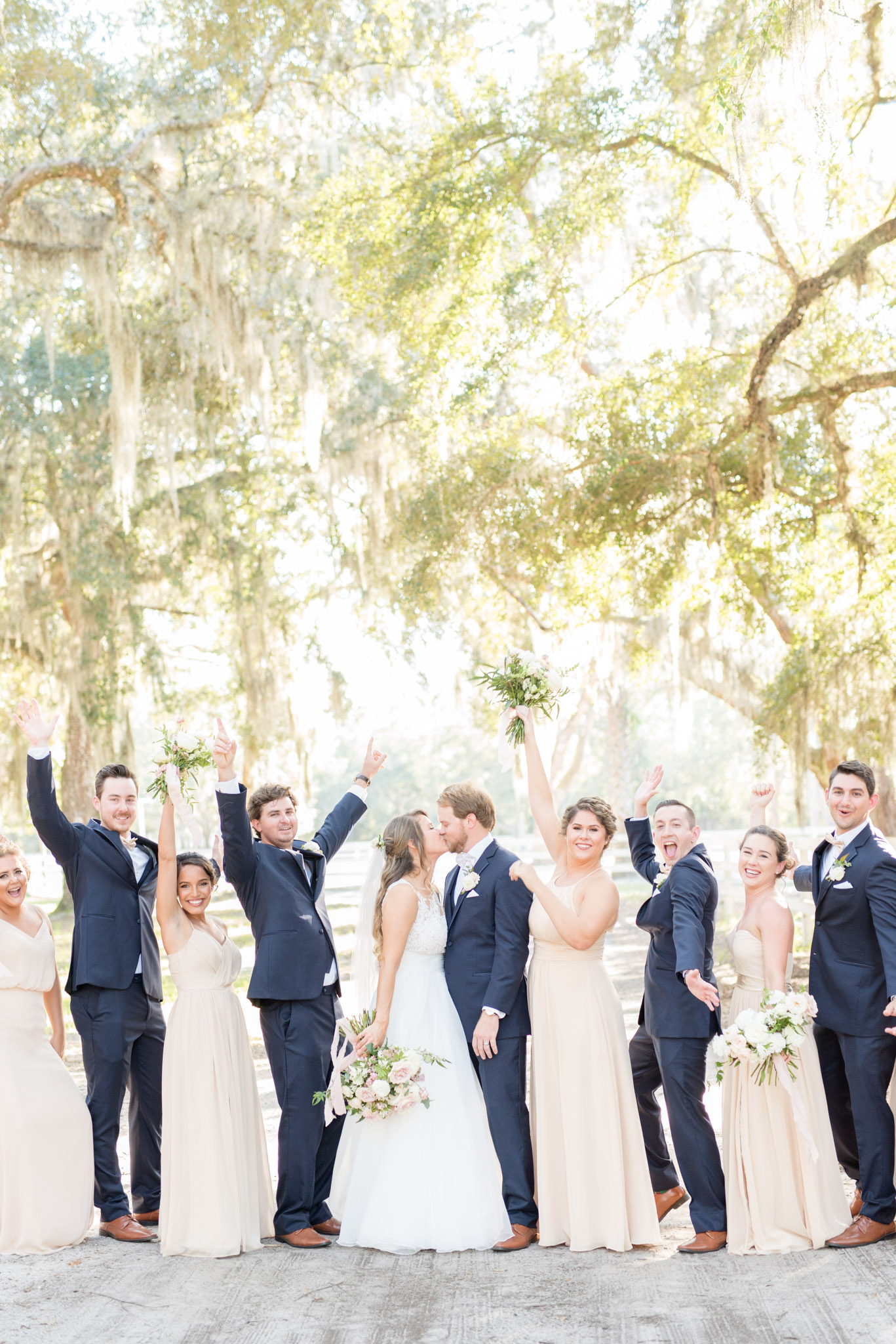 Bride and groom kiss while wedding party cheers.