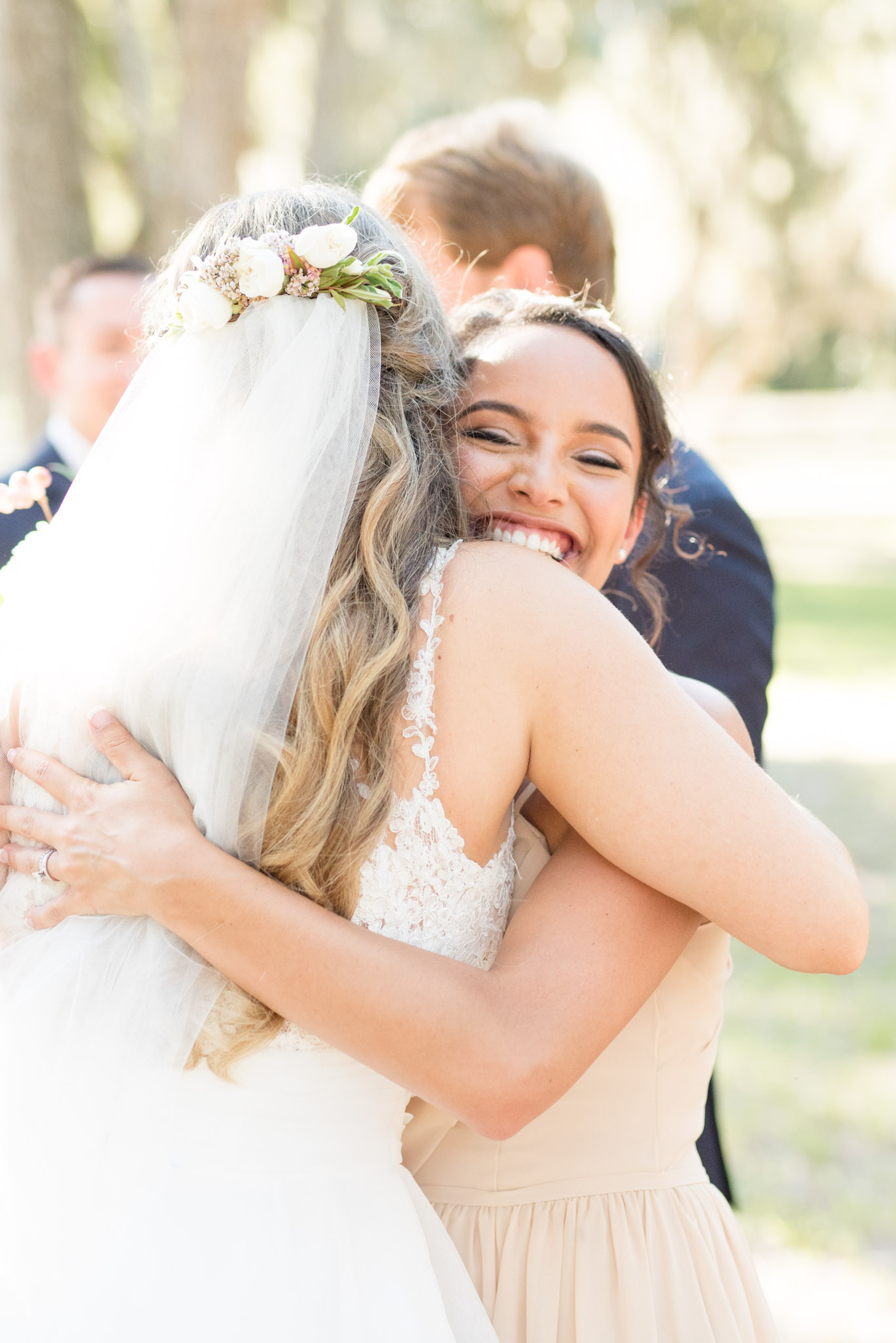 Bridesmaid hugs bride.