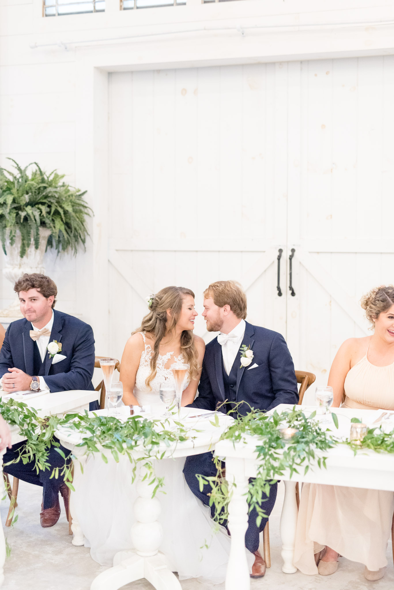 Bride and groom lean in for kiss at reception.