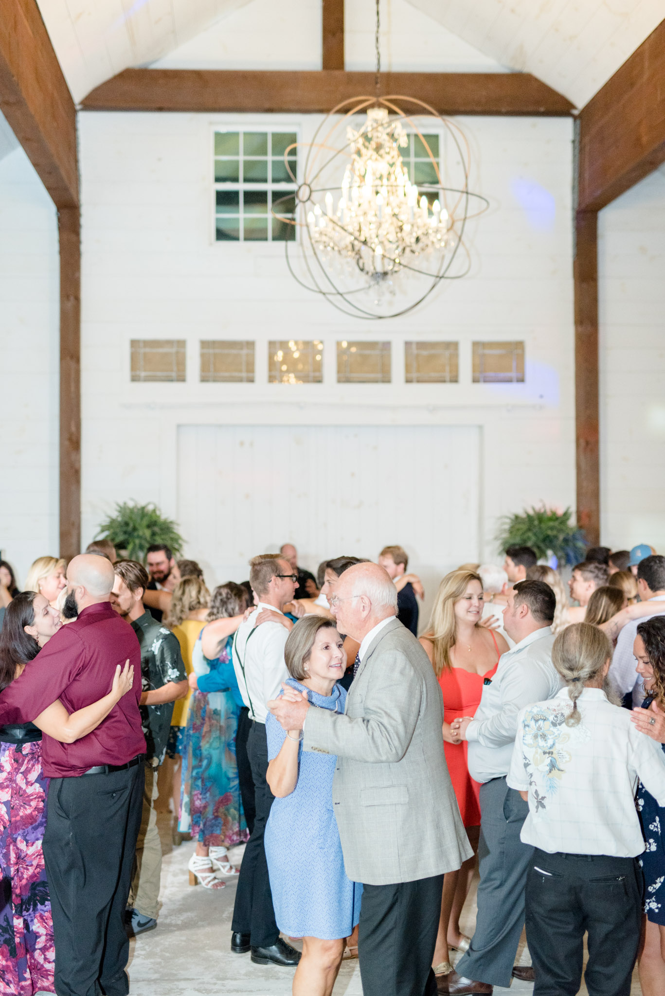 Wedding guests dance under chandelier.