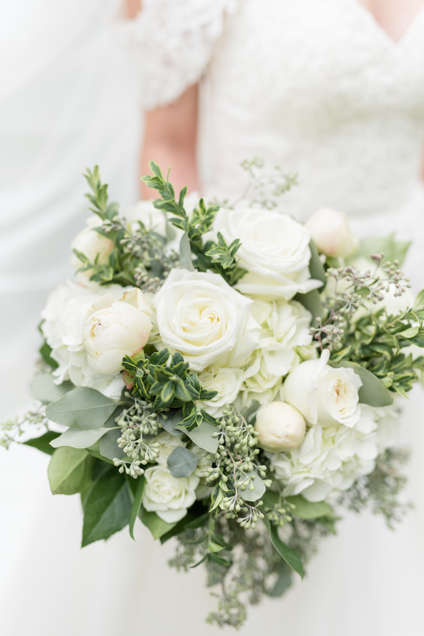 Bride holds white wedding bouquet.