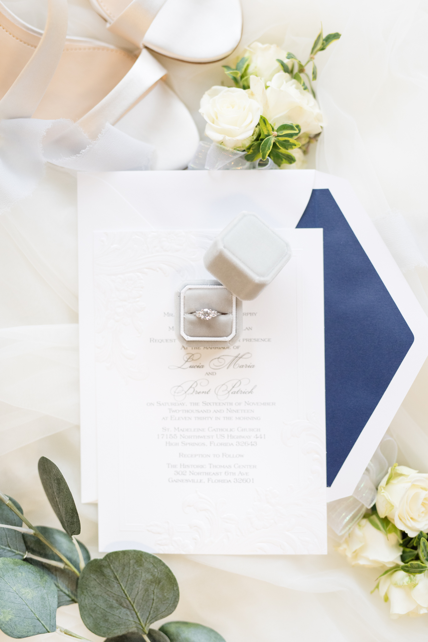 Engagement ring sits on wedding invitation.