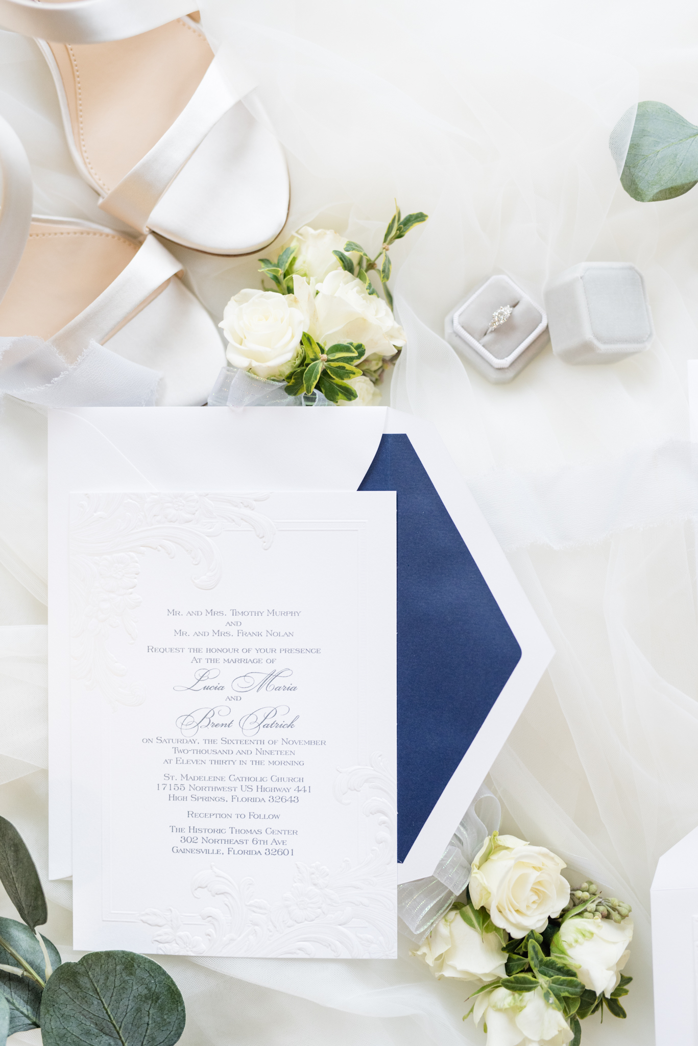 Wedding invitation sits with bridal details.