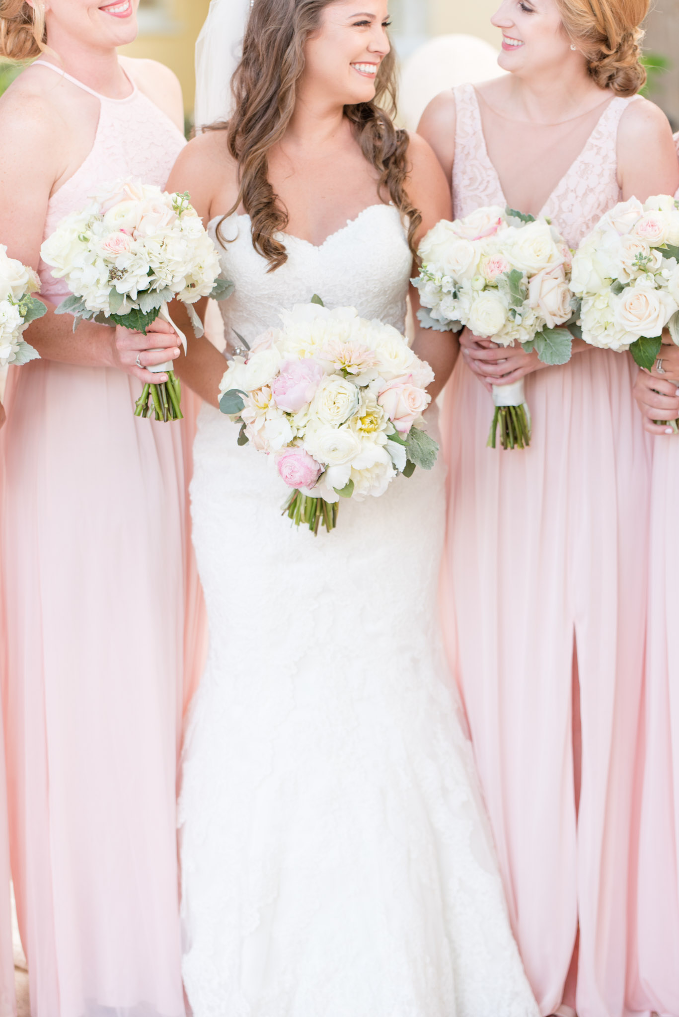 Bride and bridesmaids smile and hold flowers