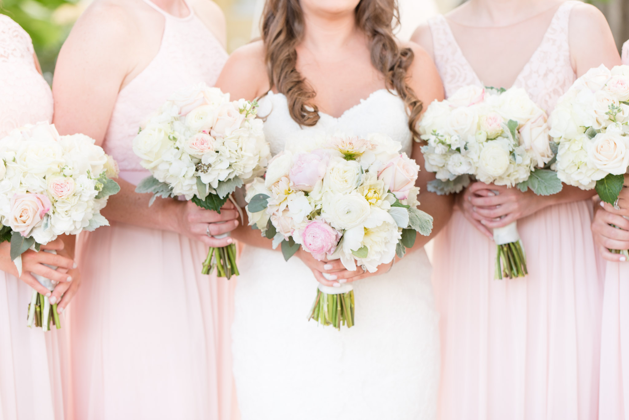 Bride and bridesmaids hold bouquets.