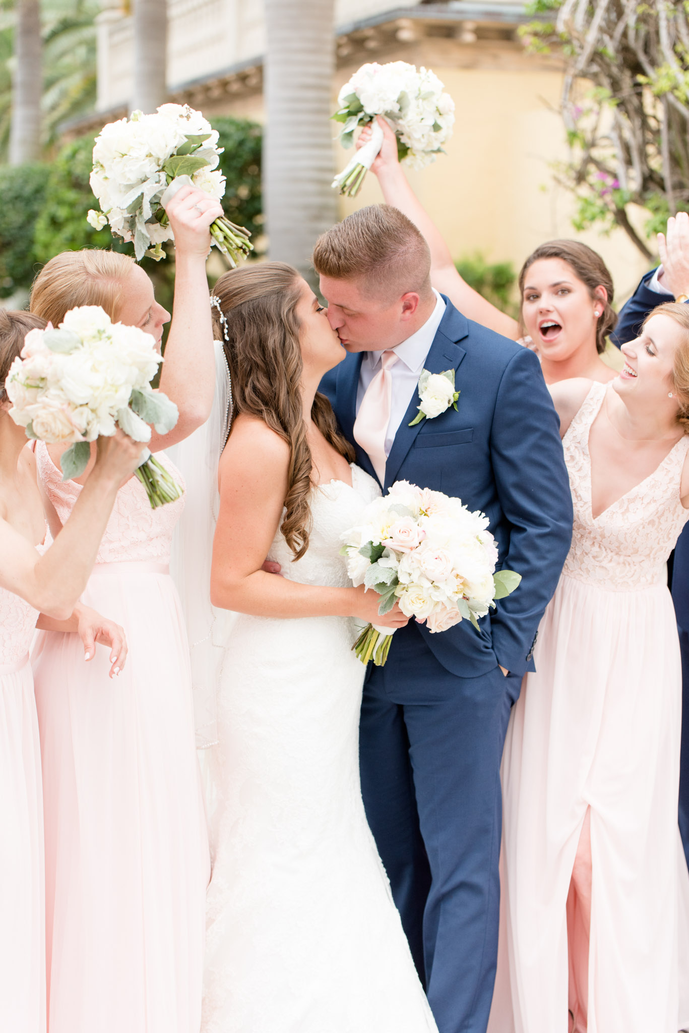 Bride and groom kiss while friends cheer.