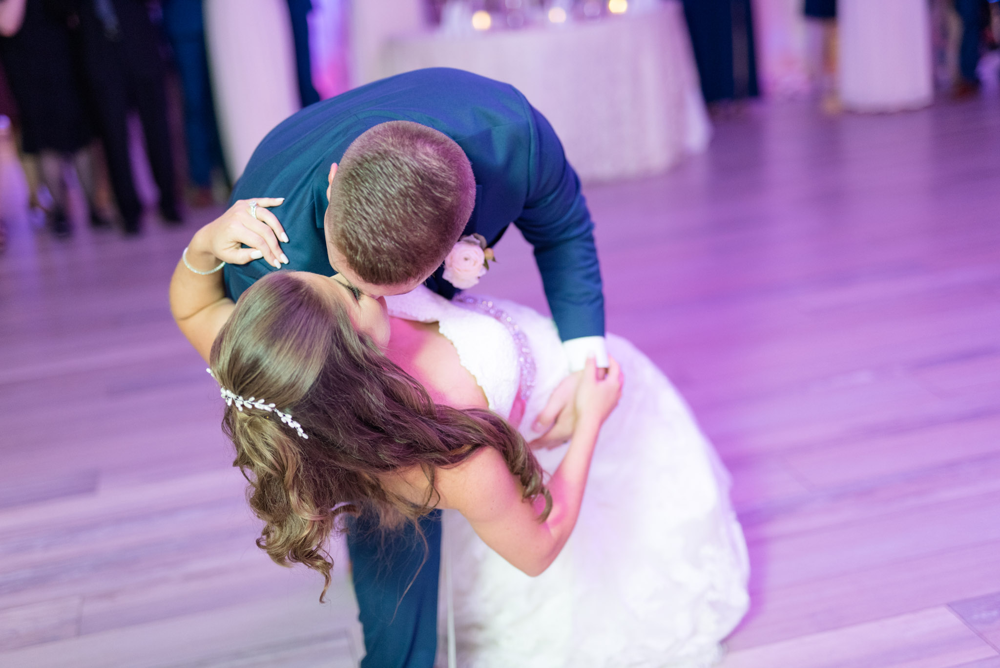 Groom dips bride on dance floor.