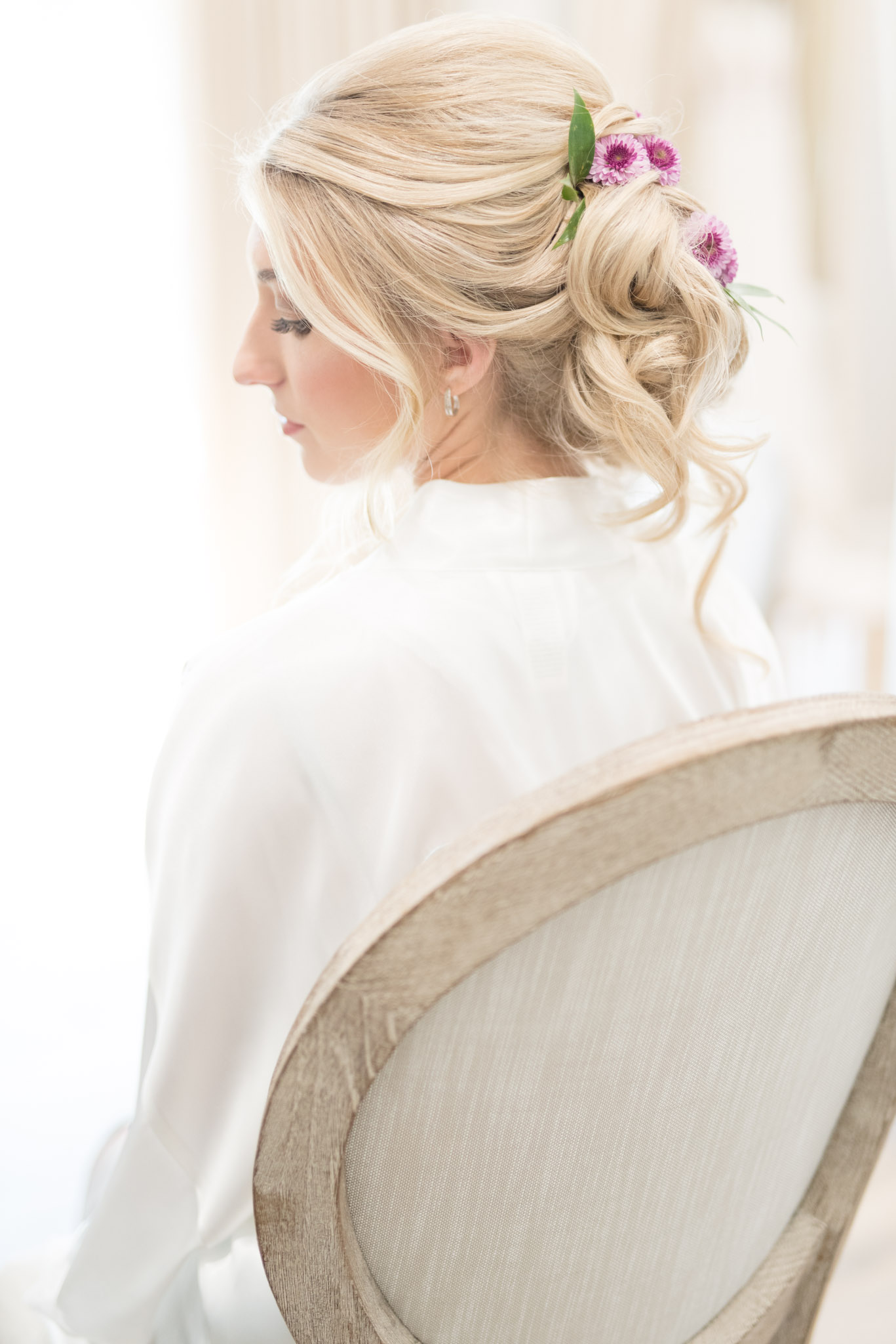 Bride looks over shoulder while getting hair done.