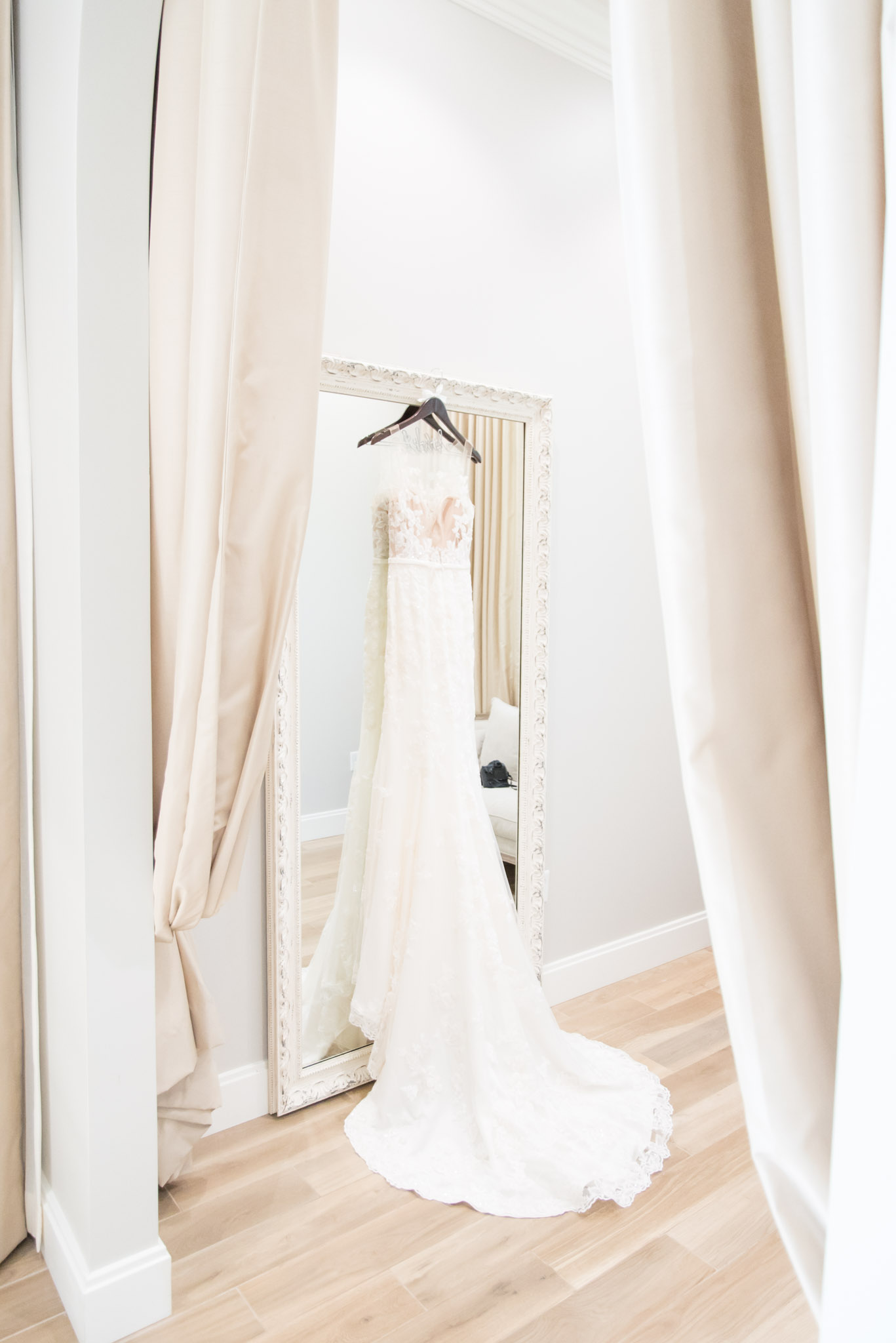 Bride's wedding dress hangs in getting ready room.