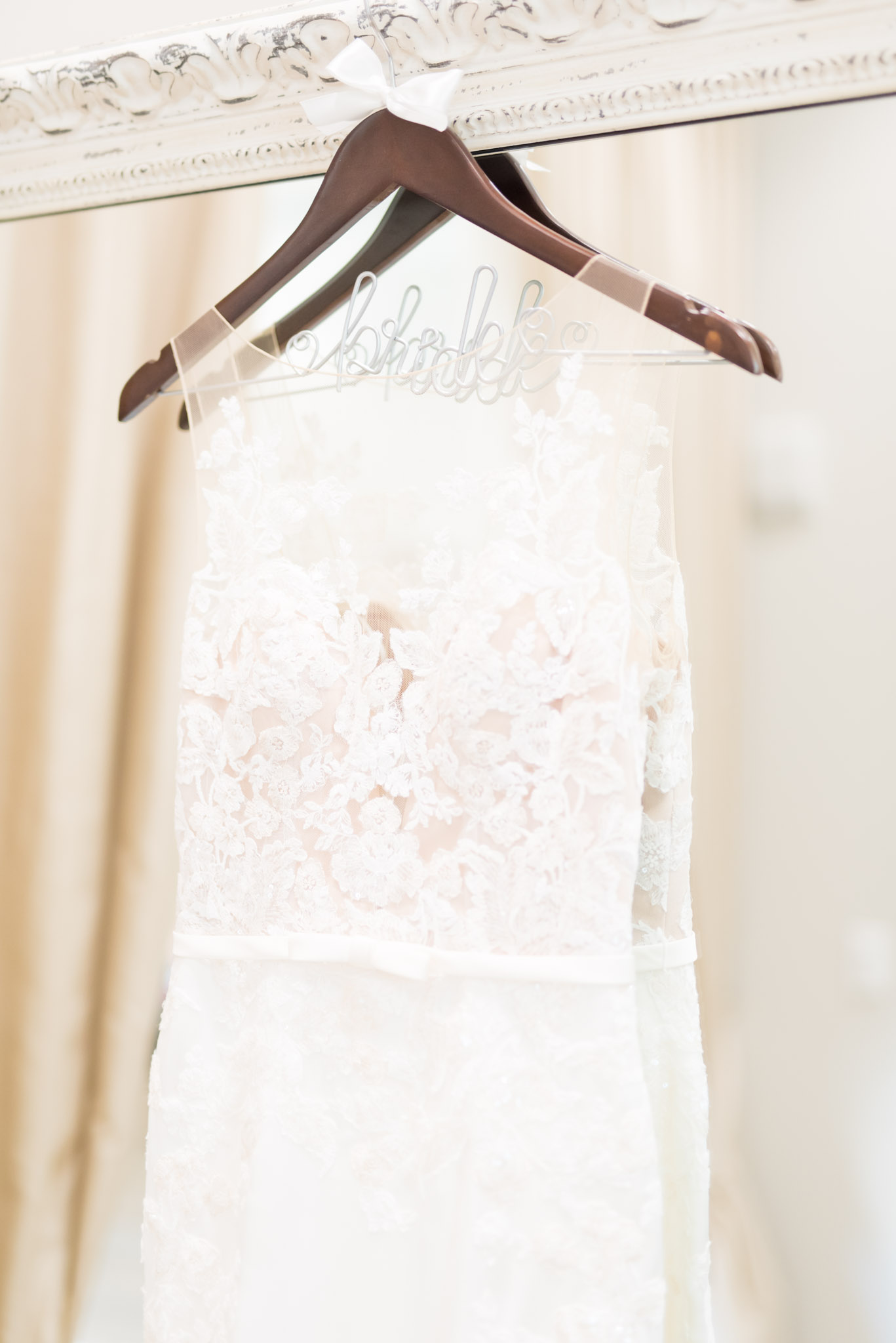 Bride's wedding gown hangs on mirror.
