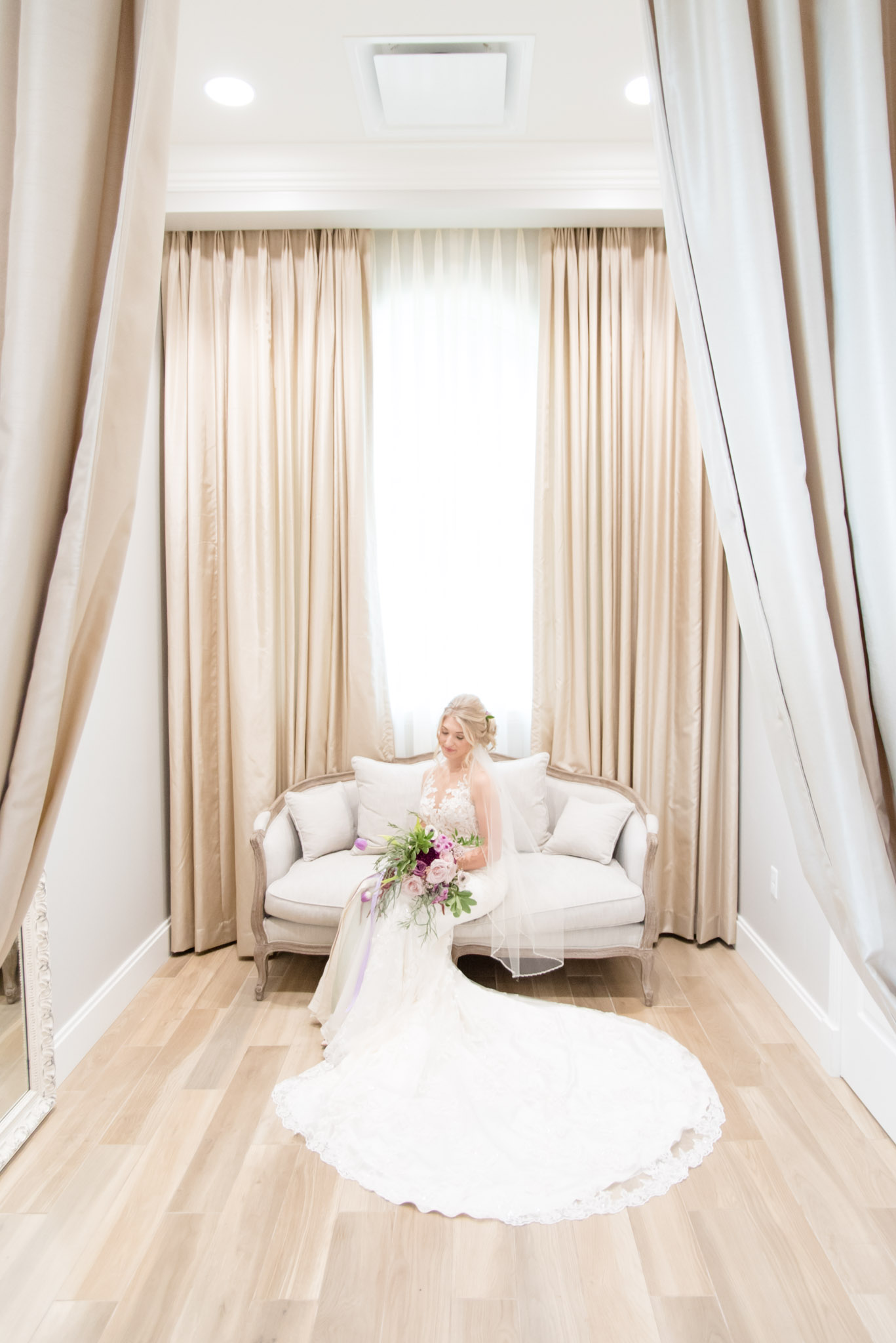 Bride looks down while sitting on couch.