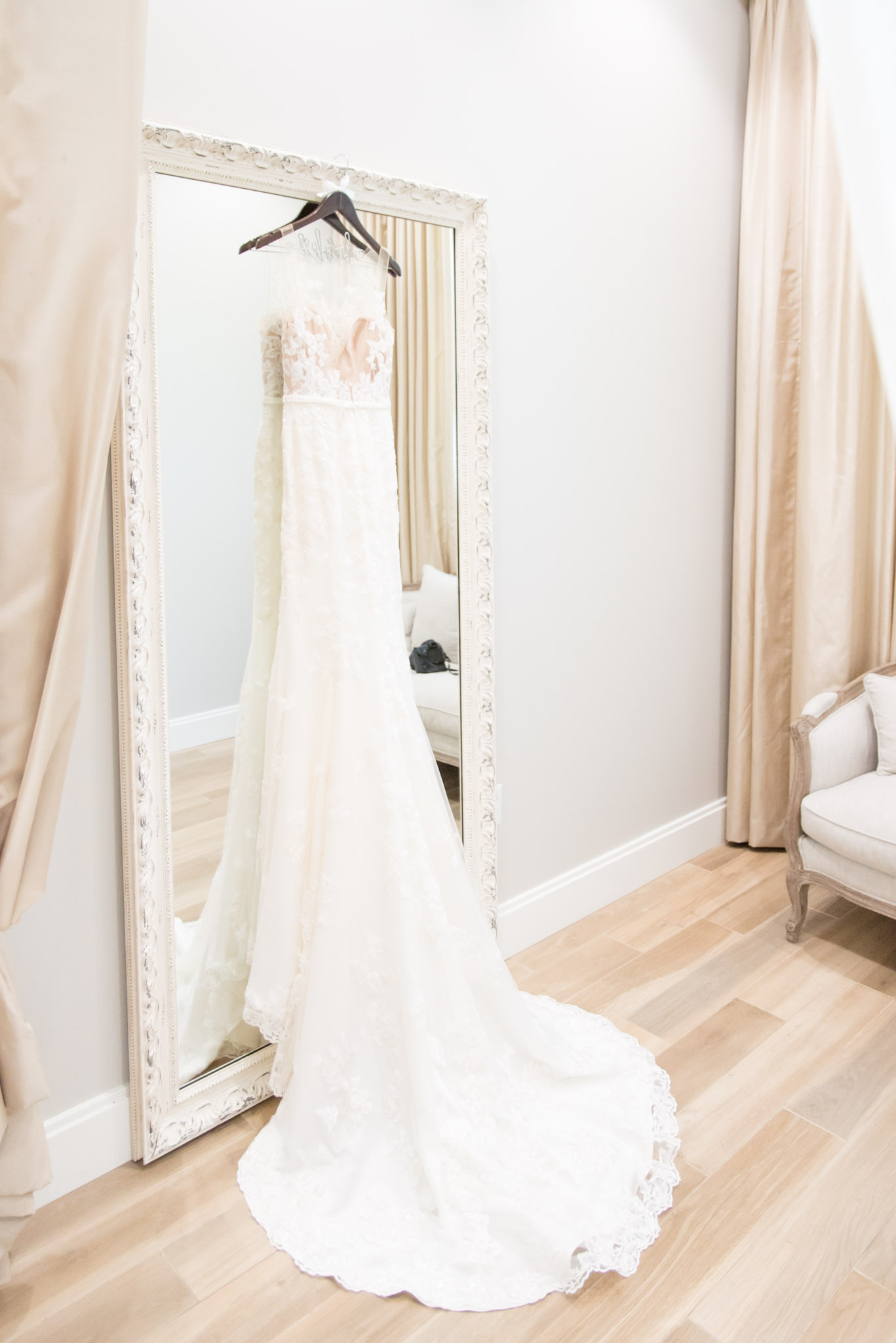 Wedding gown hangs on mirror.