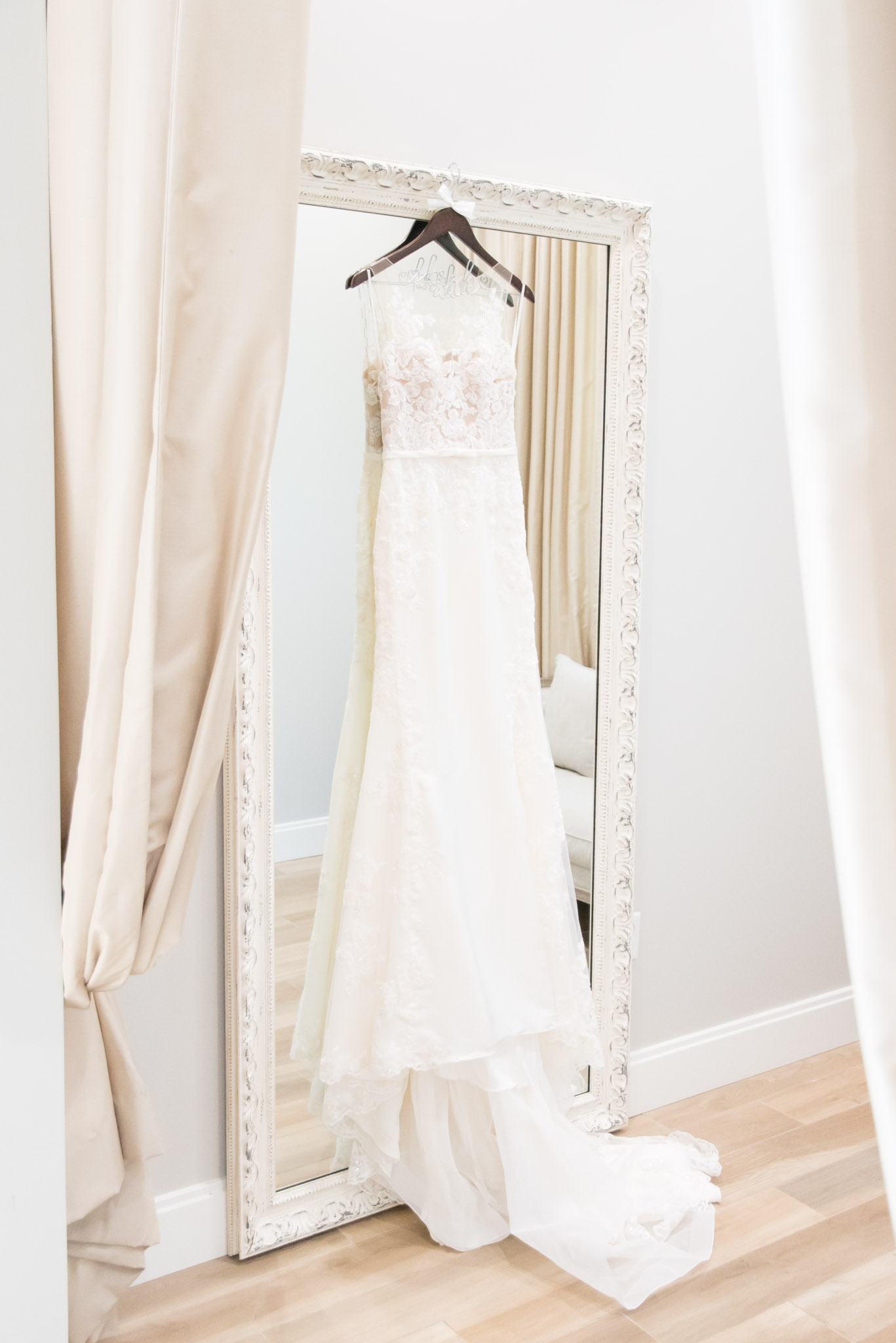 Wedding dress hangs on large mirror.