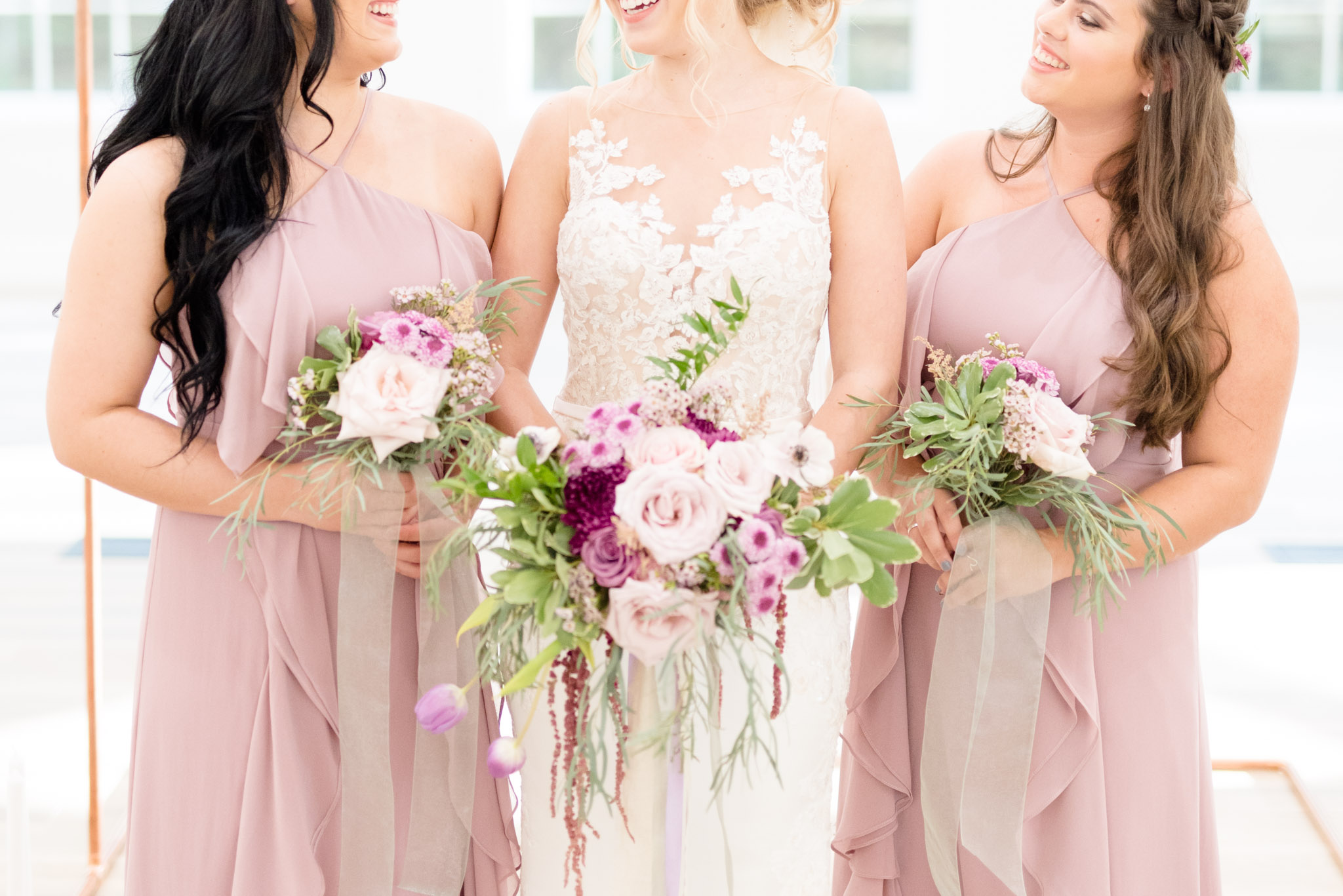 Bride and bridesmaids hold bouquets.