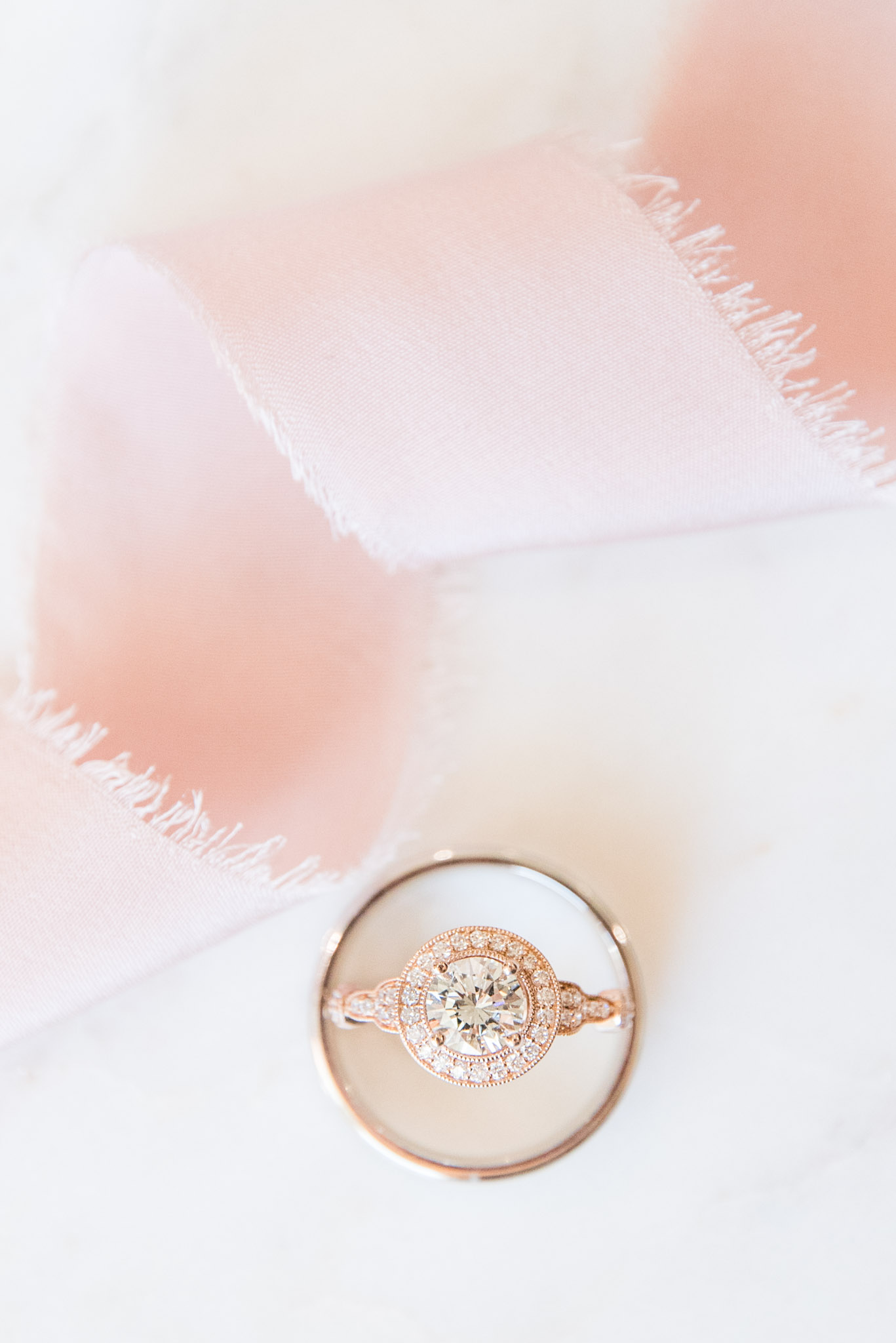 Bride's engagement ring sits with pink ribbon.