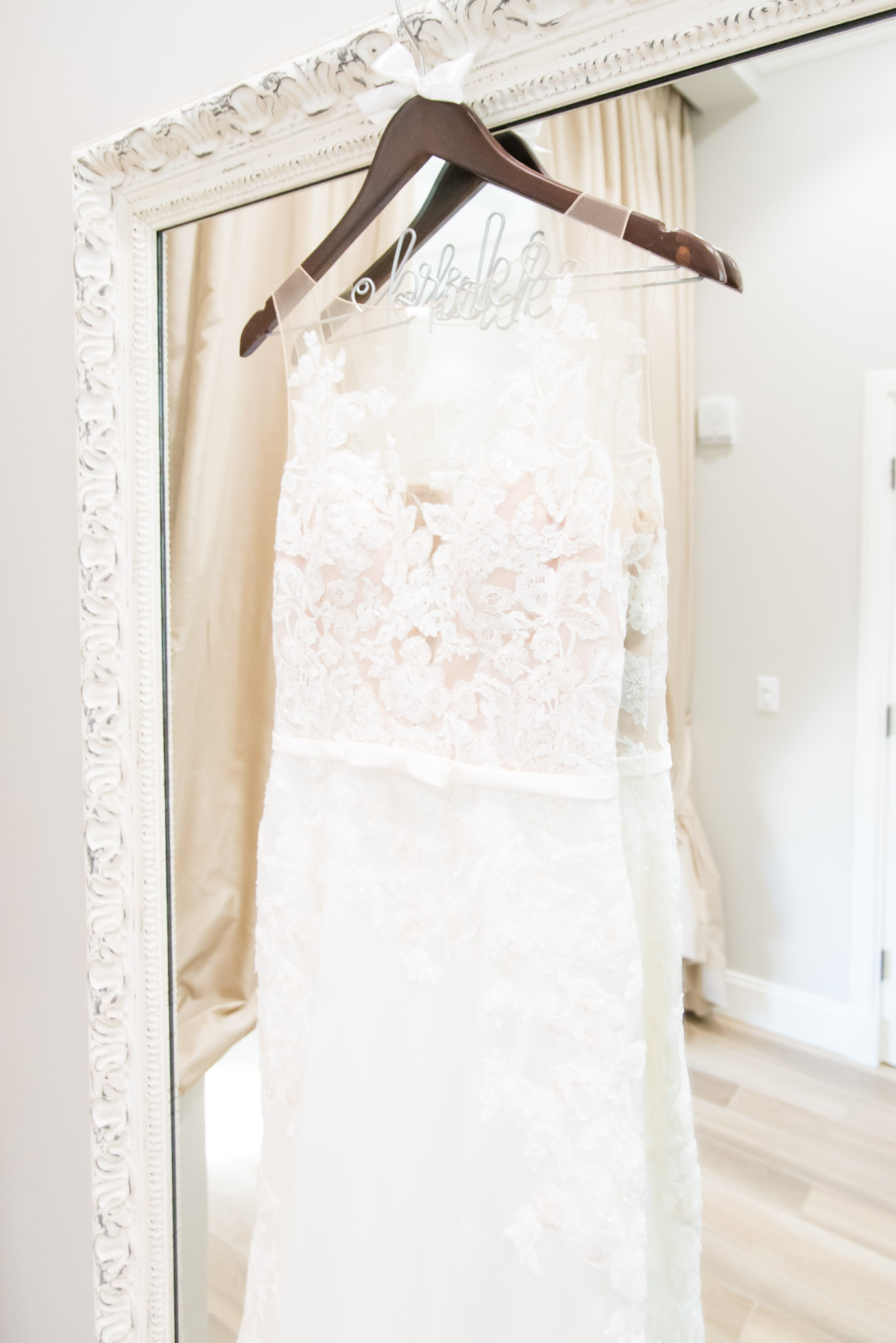 Brides dress hangs on mirror.
