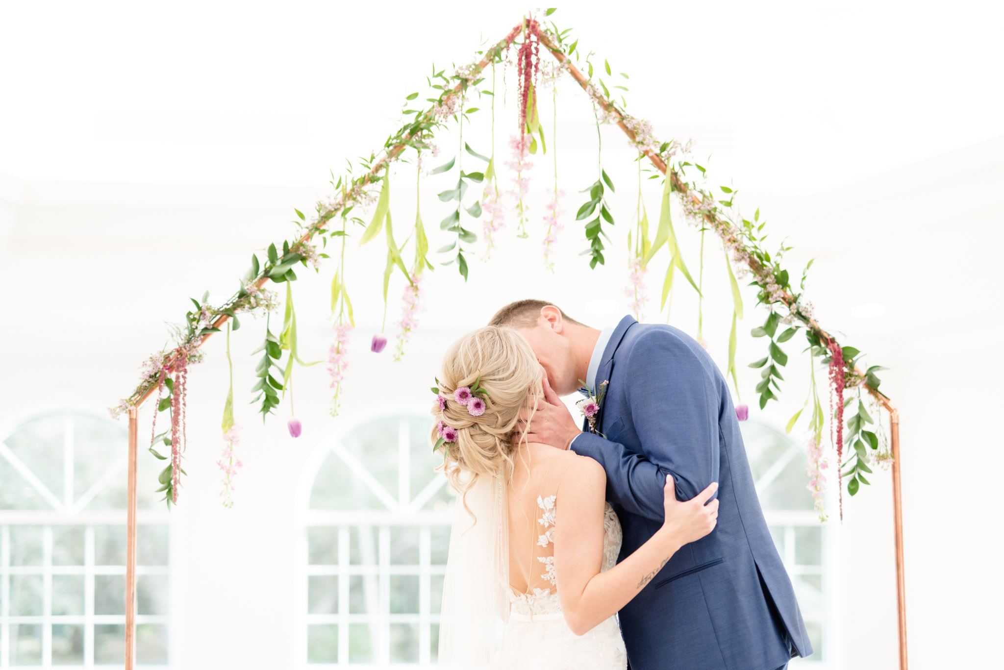 Bride and groom kiss at altar during ceremony.