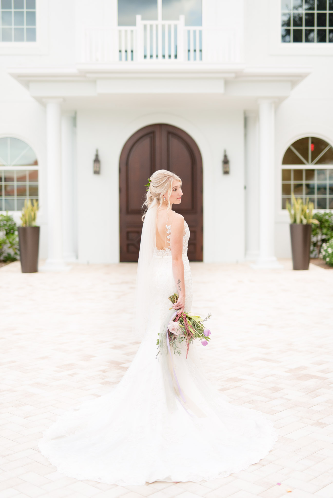 Bride looks over shoulder at white chapel.