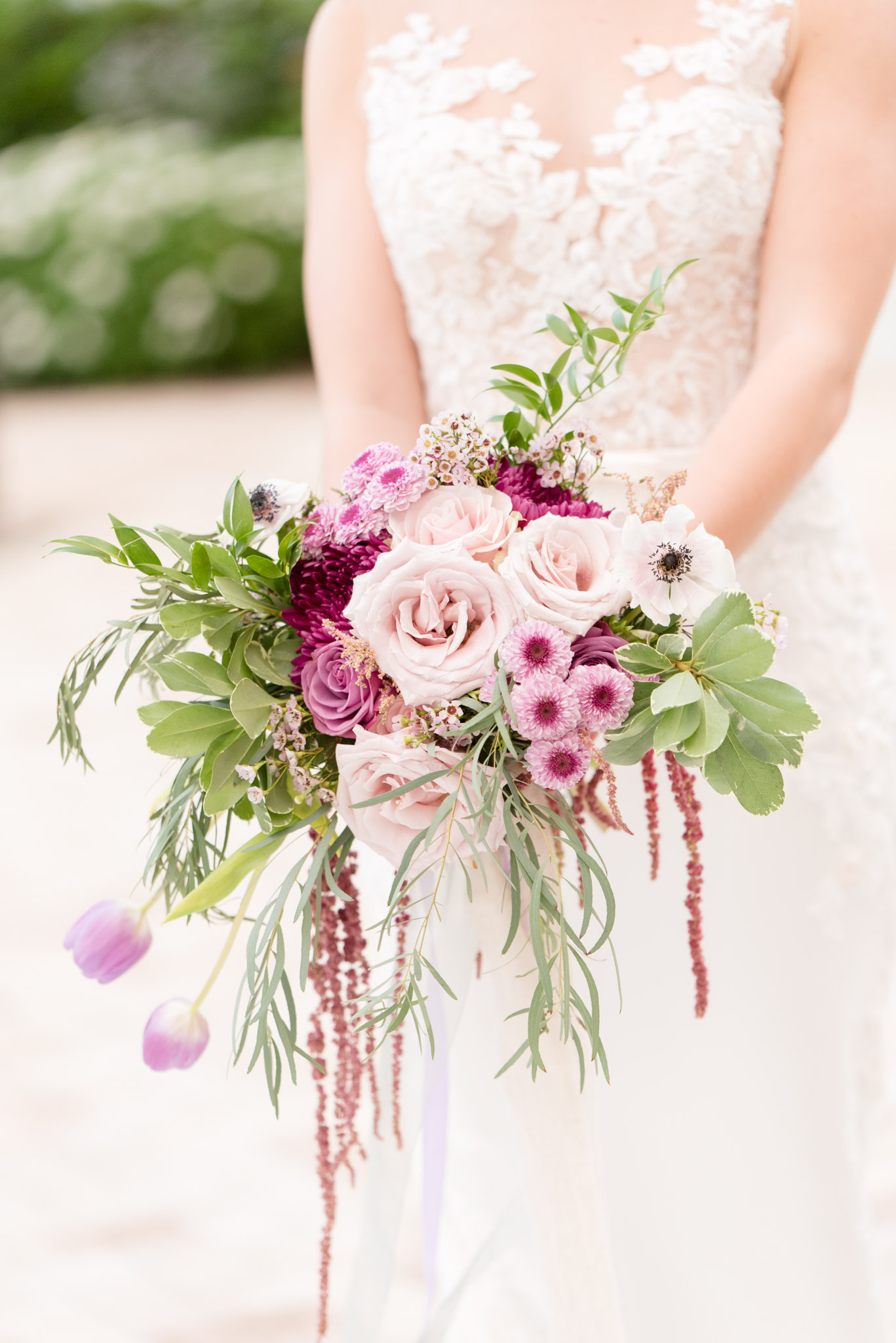 Bride holds purple flower bouquet.