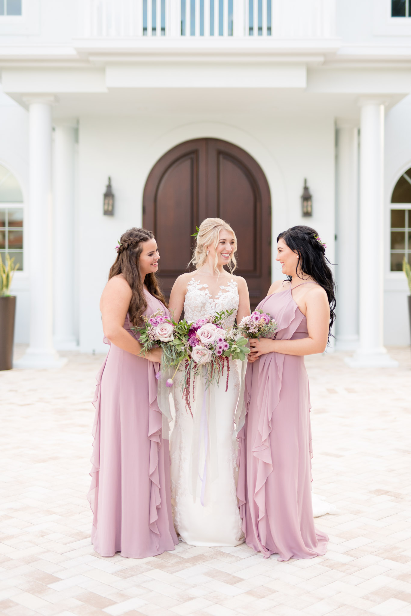 Bride and bridesmaids laugh outside of chapel.