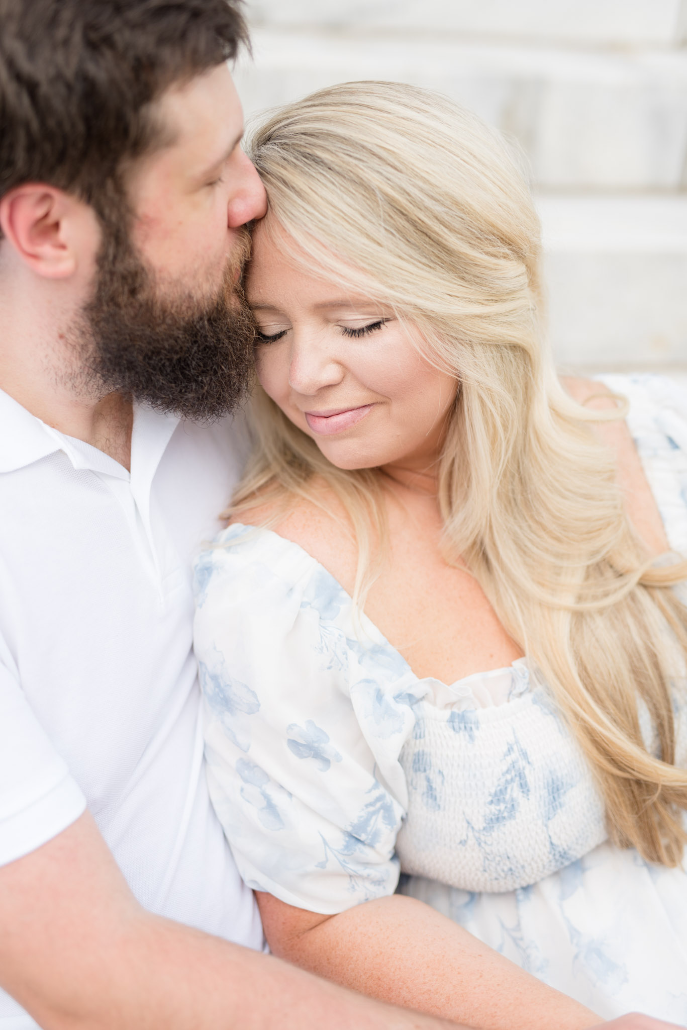 Husband kisses wife on forehead.