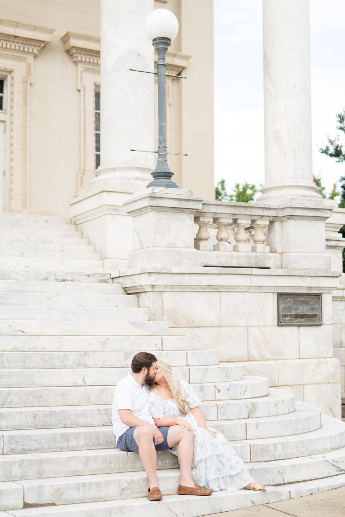 Husband and Wife kiss while sitting on stairs.