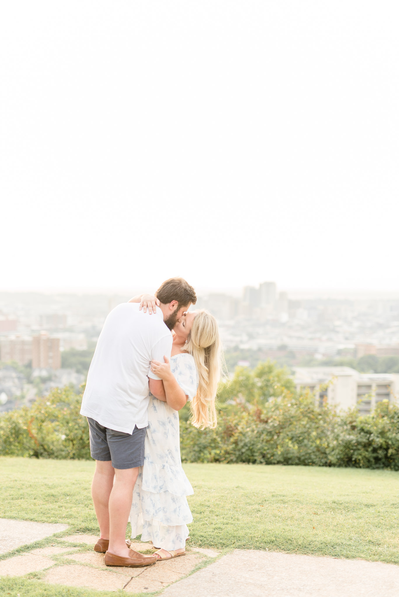 Husband dips wife back for a kiss at city overlook.