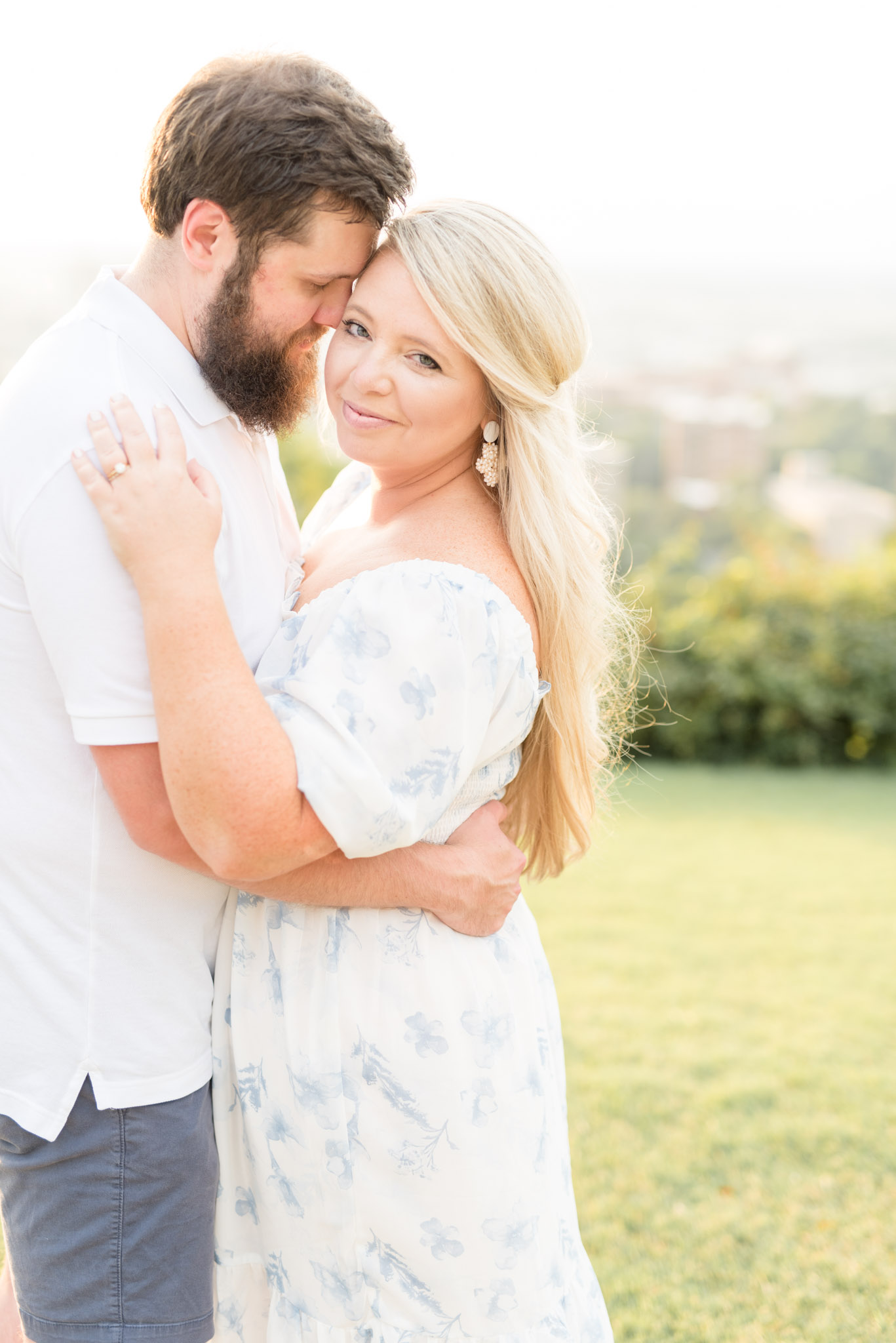 Woman looks at camera while husband cuddles her.