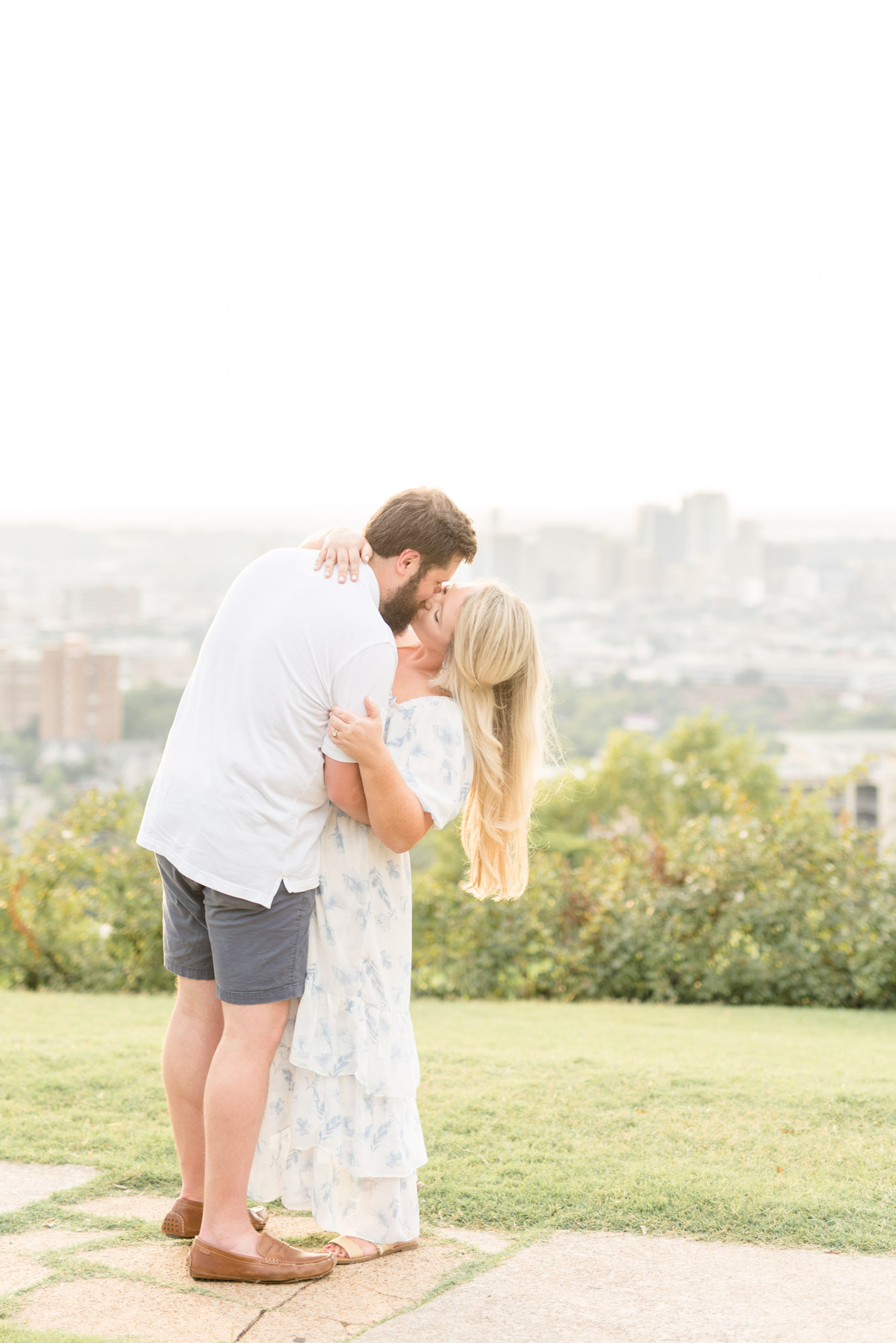 Couple kisses at city overlook.