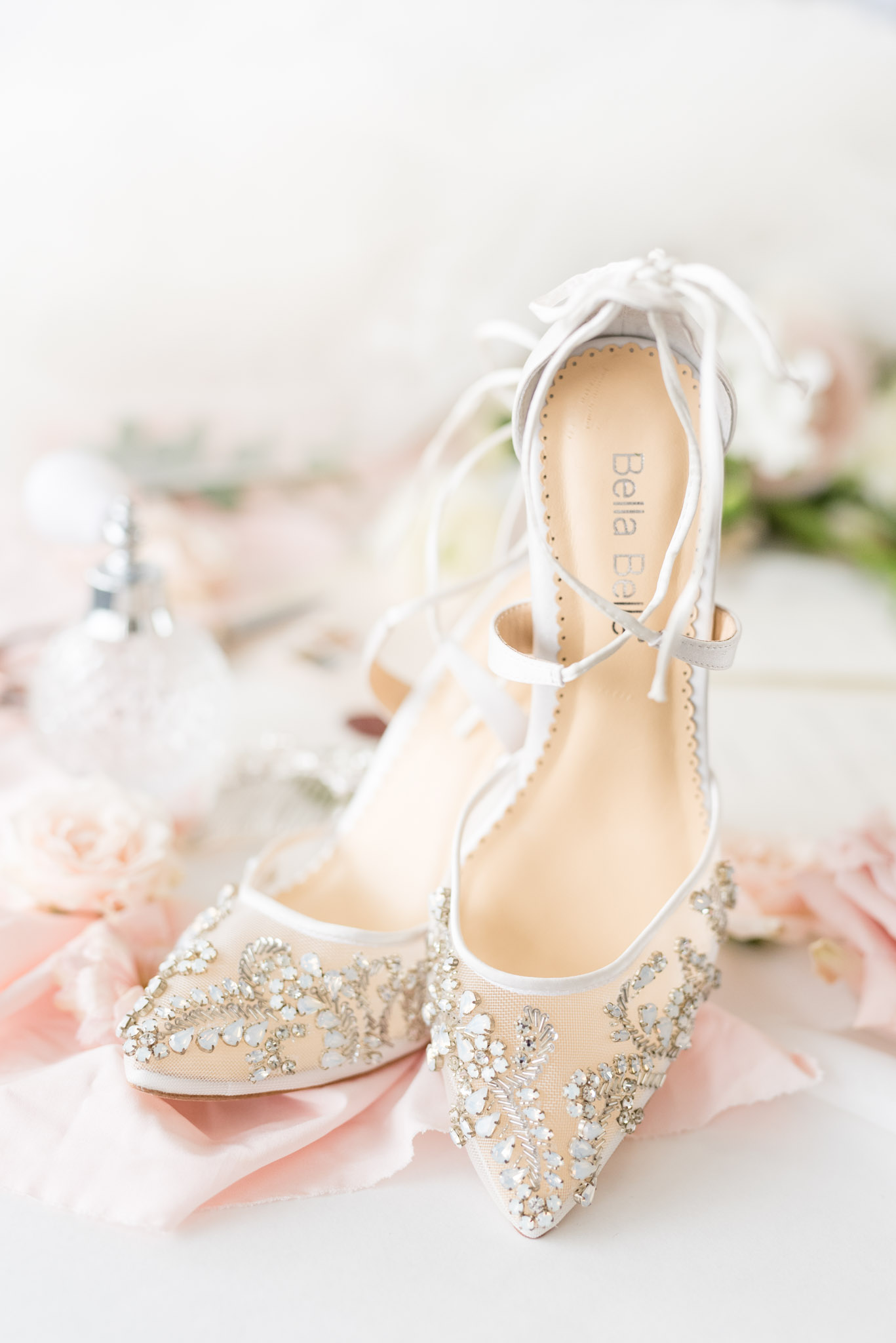 Jeweled wedding shoes sit on ribbon.
