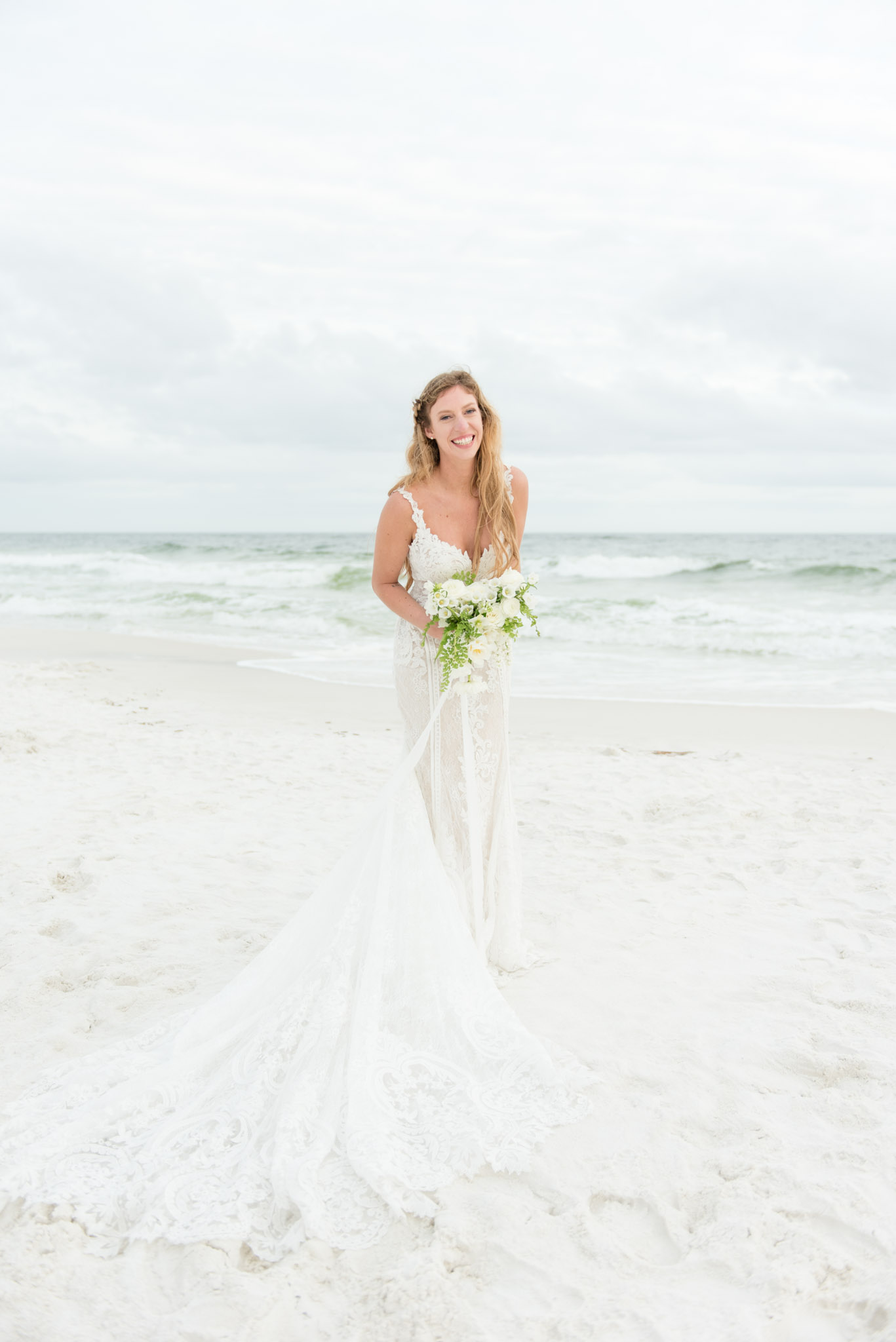 Bride laughs on beach.