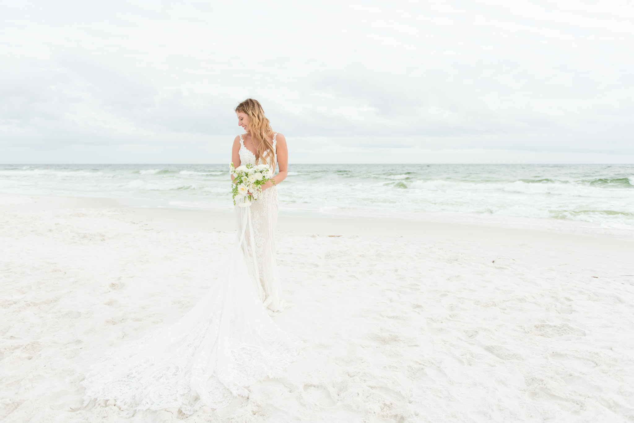 Bride smiles by ocean.