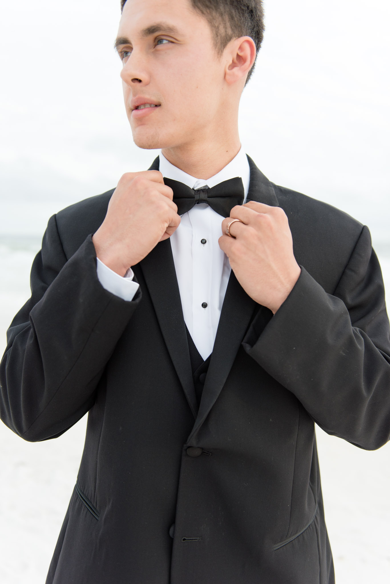 Groom straightens bow tie.