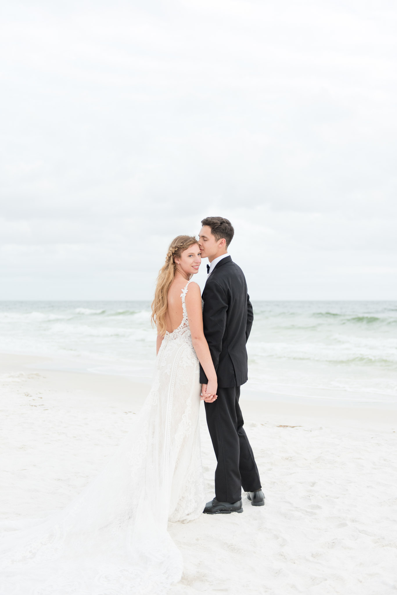 Groom kisses bride as she looks over her shoulder.