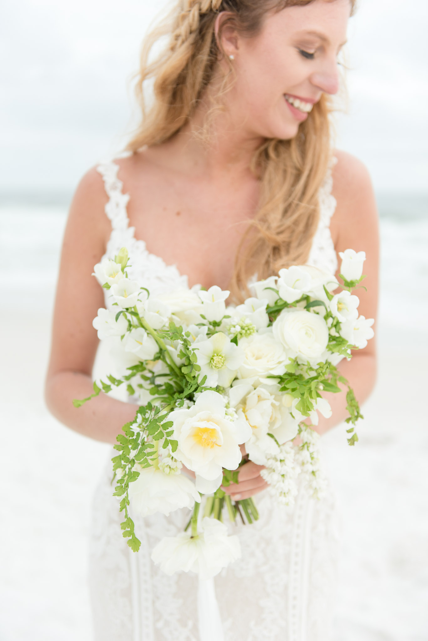Bride smiles as she holds bouquet.