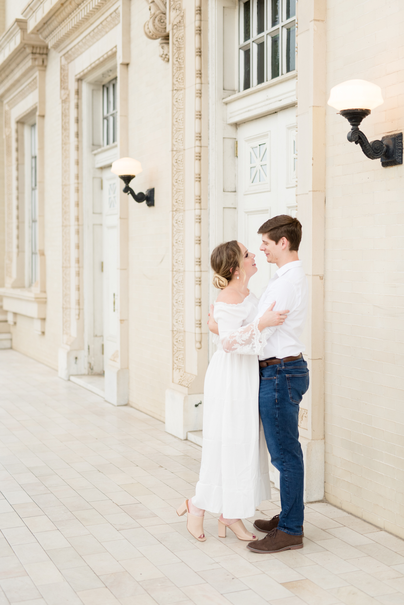 Engaged couple snuggles in front of white doors
