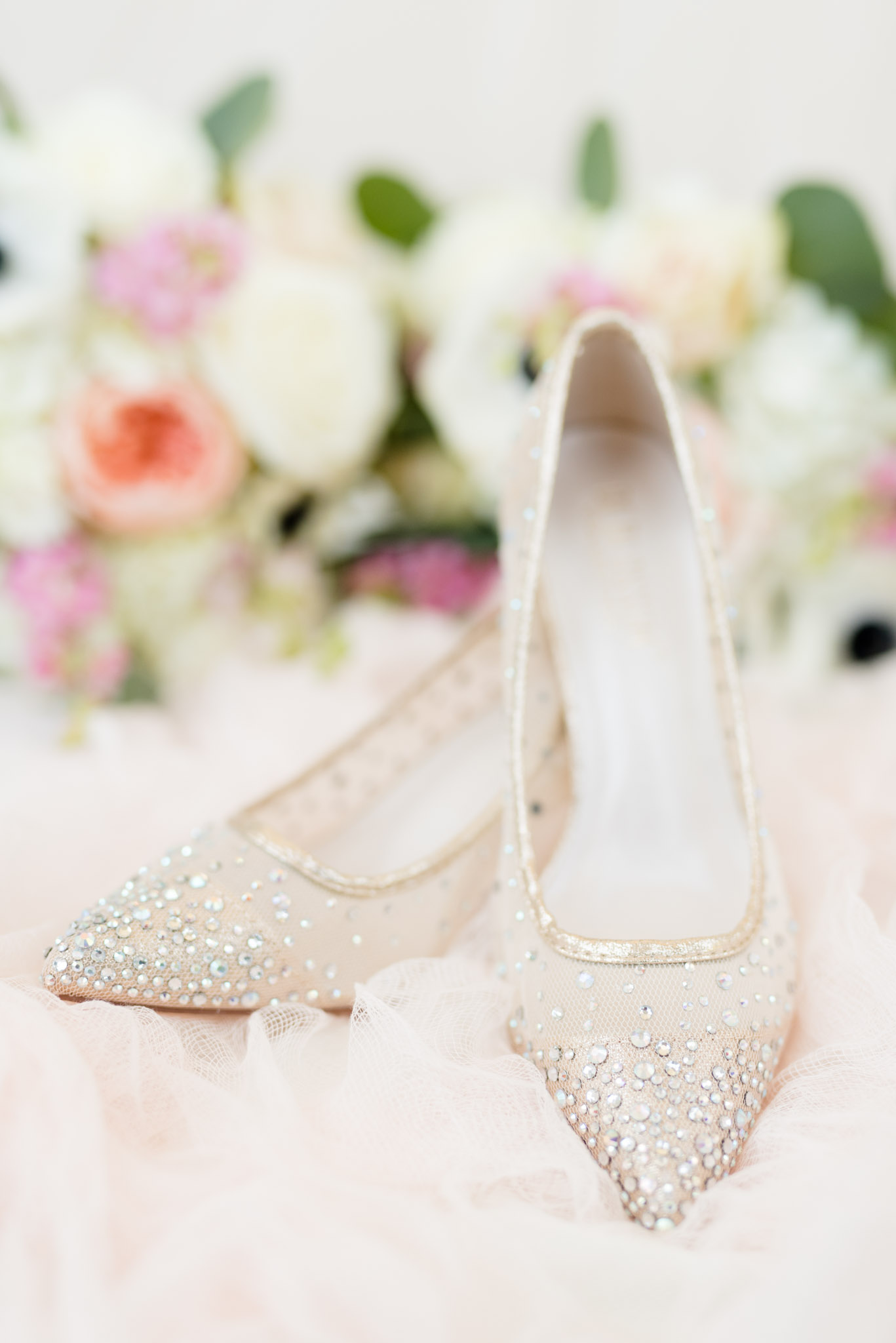 Bridal shoes sit on pink tulle.