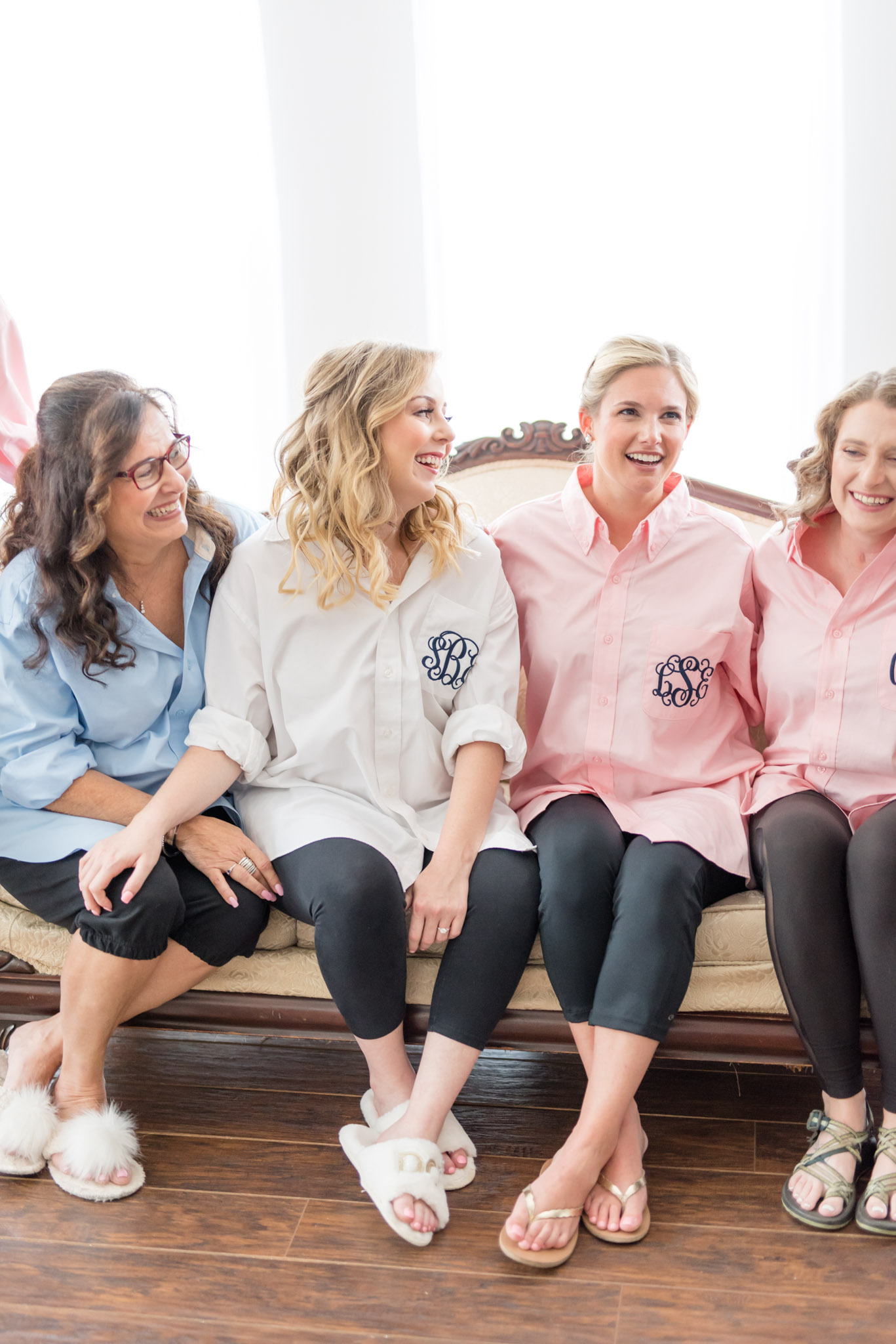 Bride, mom, and bridesmaids laugh together.