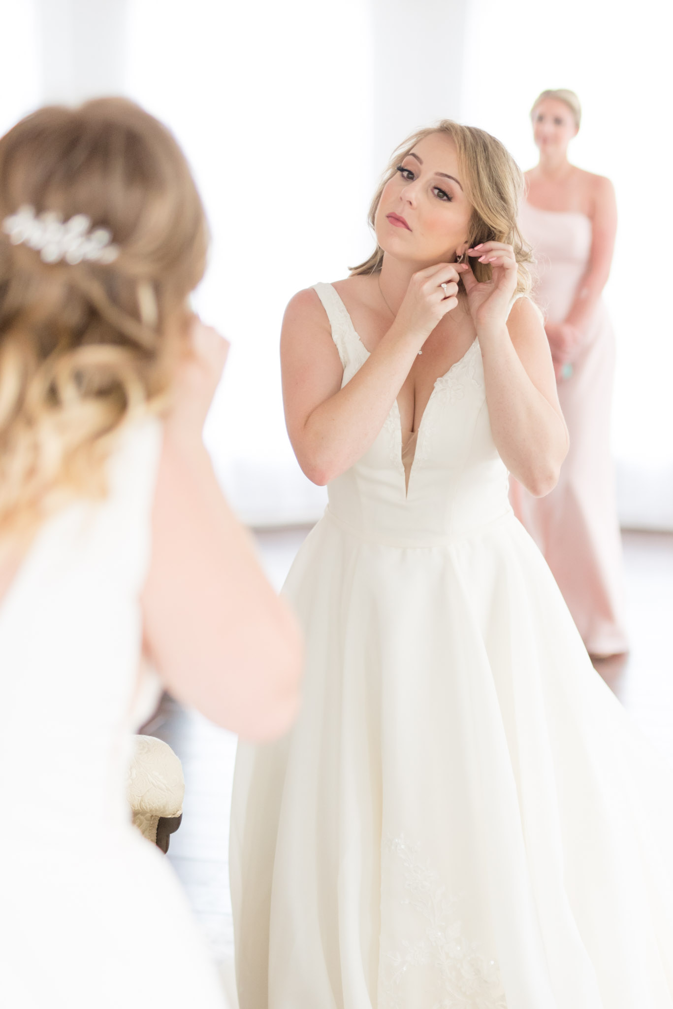 Bride puts in earrings in mirror.