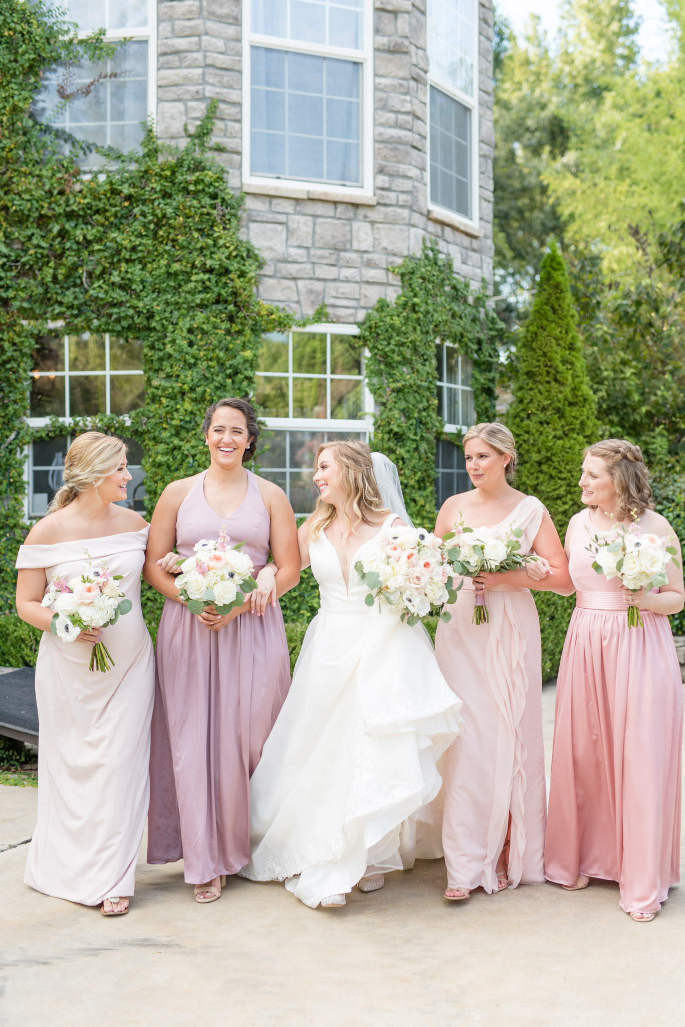 Bride and bridesmaids walk and smile together.