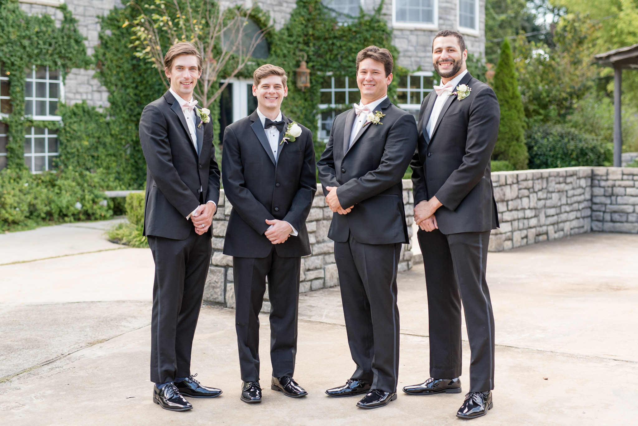 Groom and groomsmen smile at the camera.