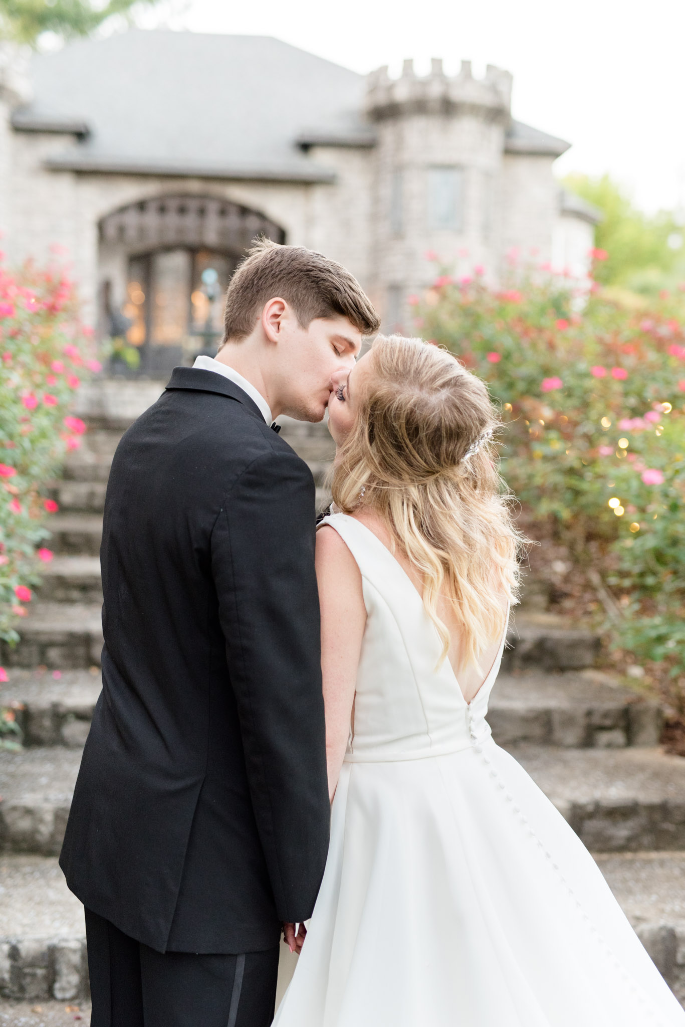 bride and groom kiss in front of castle stairs.
